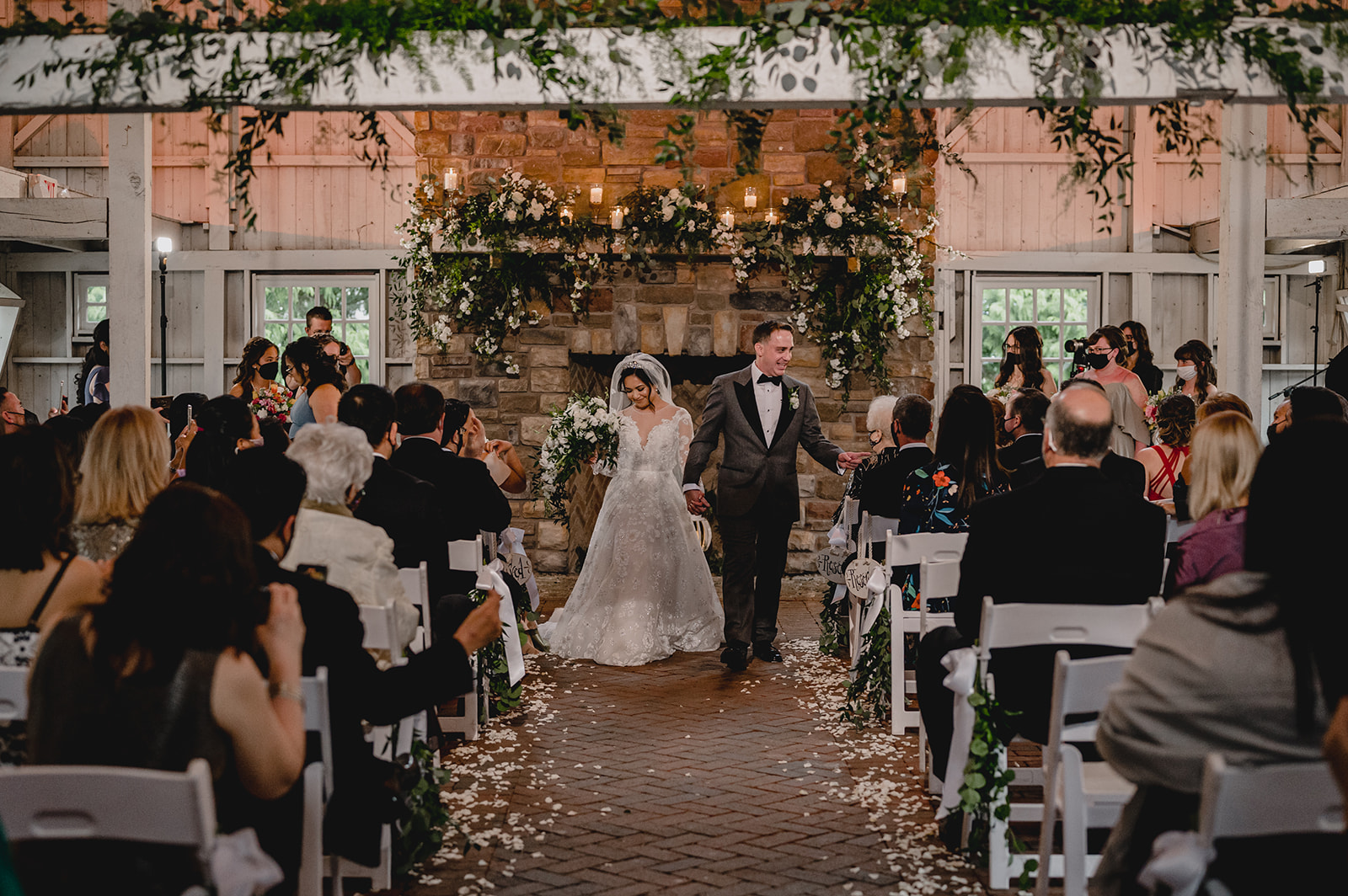 bride and groom greet guests walking up aisle in barn at Ashford Estate