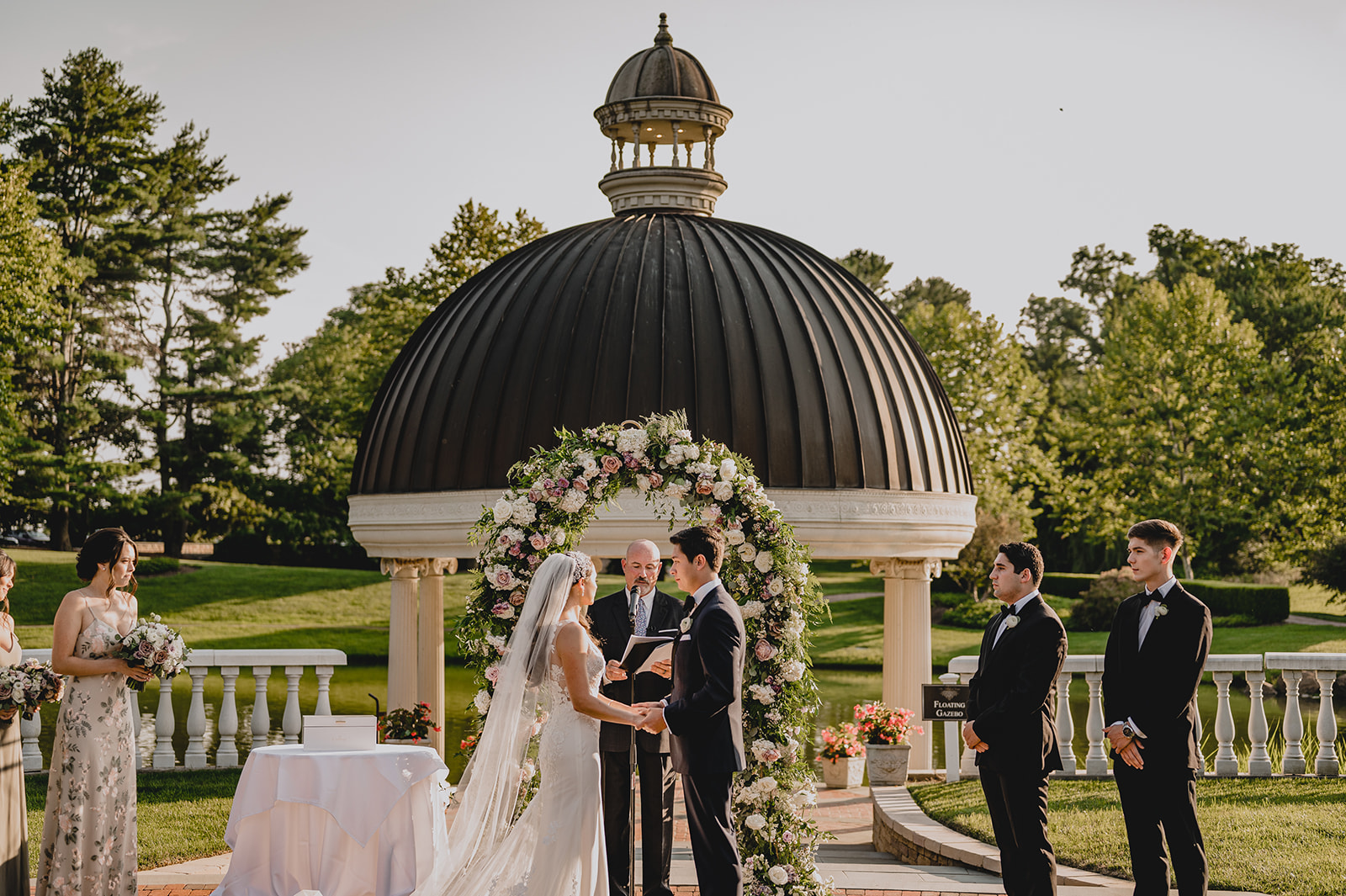 bride and groom hold hands during ceremony at the floating gazebo at Ashford Estate