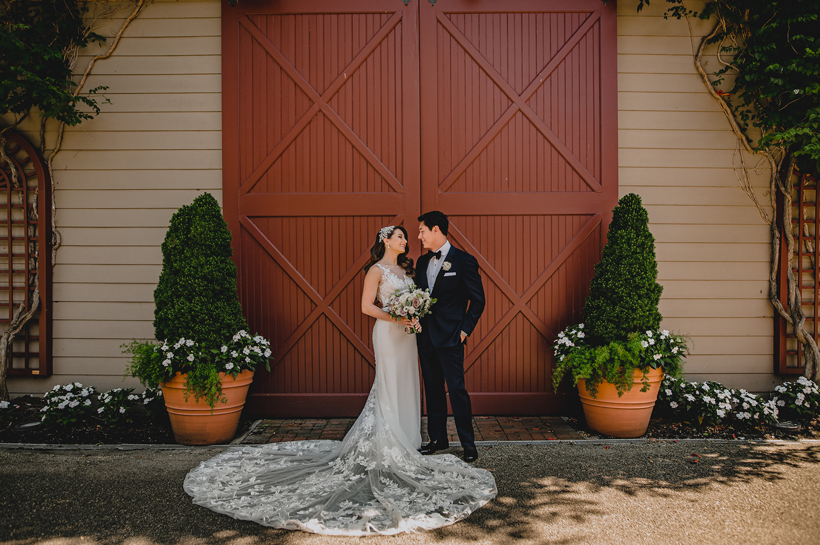 bride and groom hug by red barn door at Ashford Estate