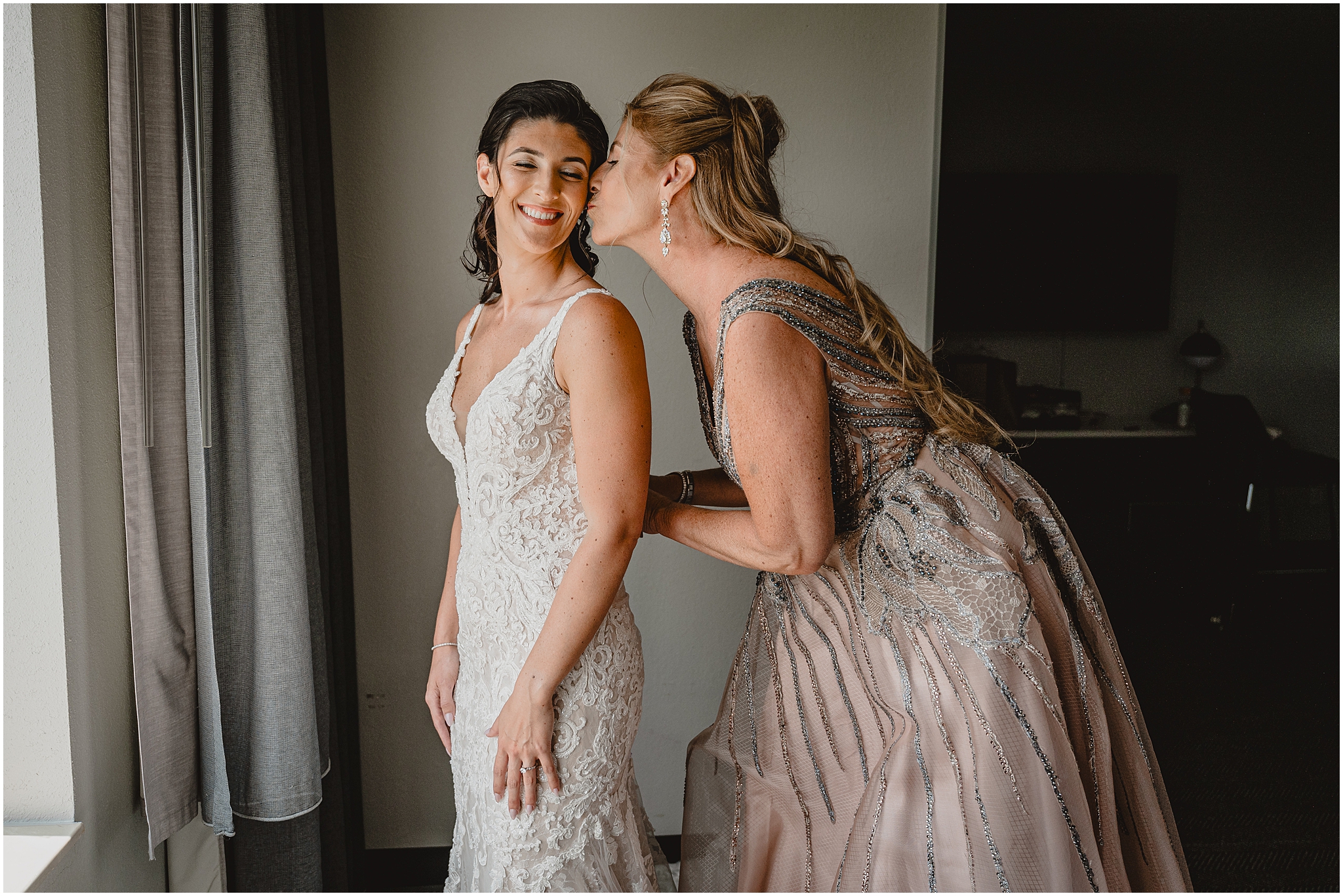 mother kisses bride's cheek while buttoning up her wedding dress during prep for NJ wedding day