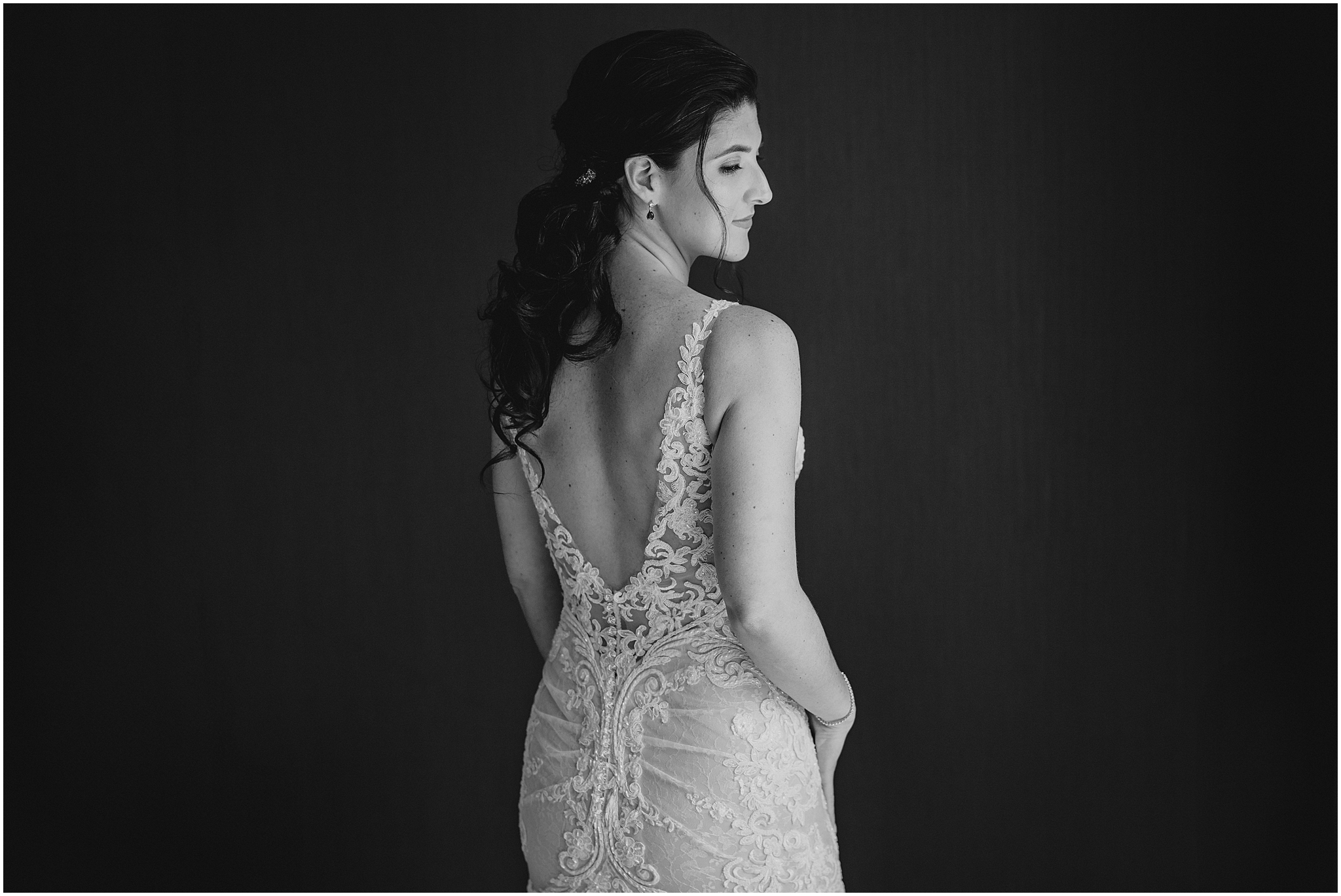bride looks over shoulder showing off lace back of wedding gown