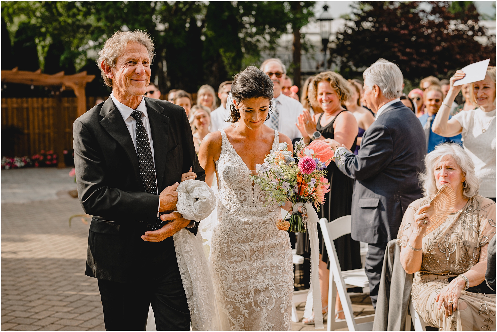 father walks bride down the aisle for wedding ceremony on patio 