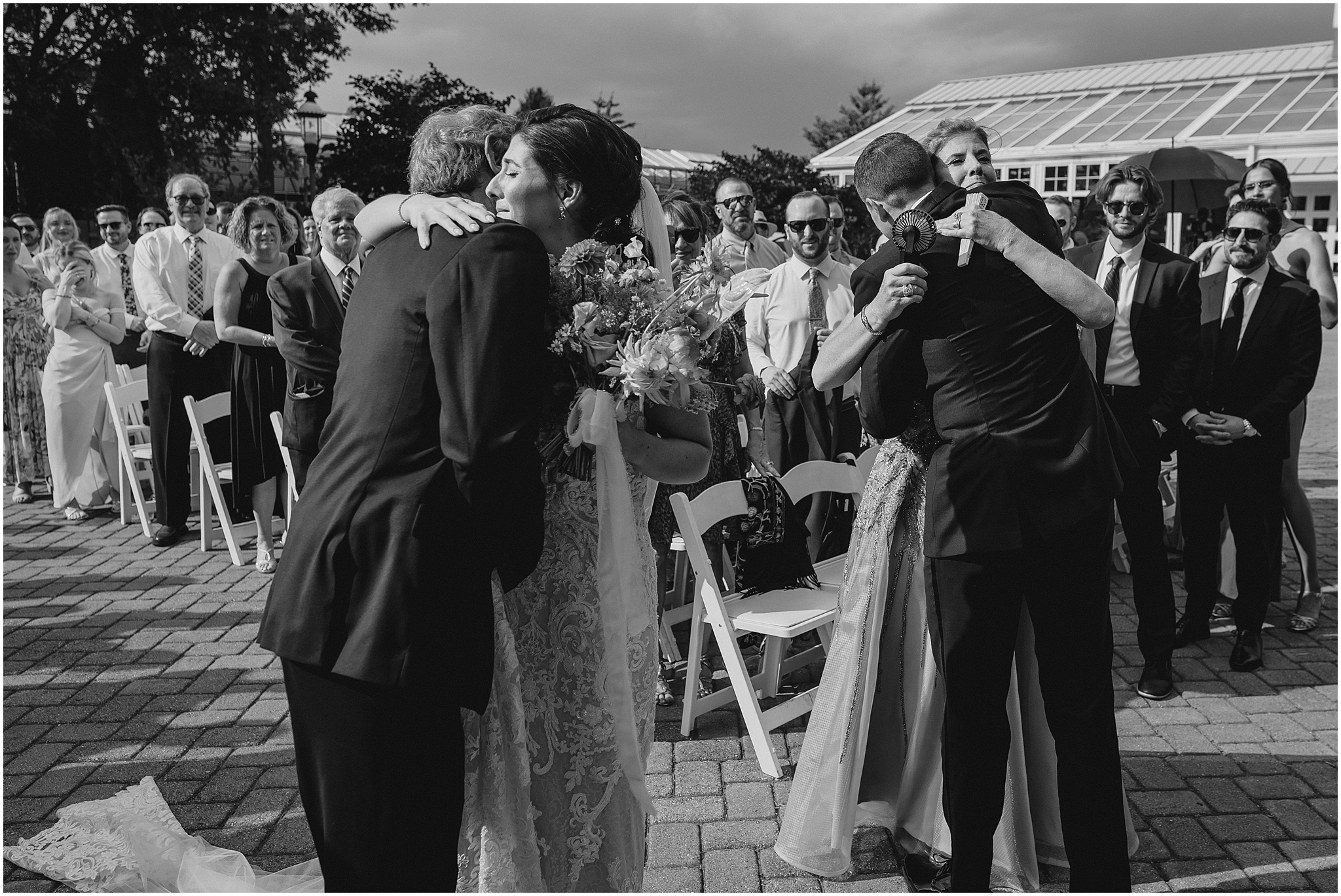 bride and groom hug parents during wedding ceremony outside the Conservatory at Sussex County Fairgrounds