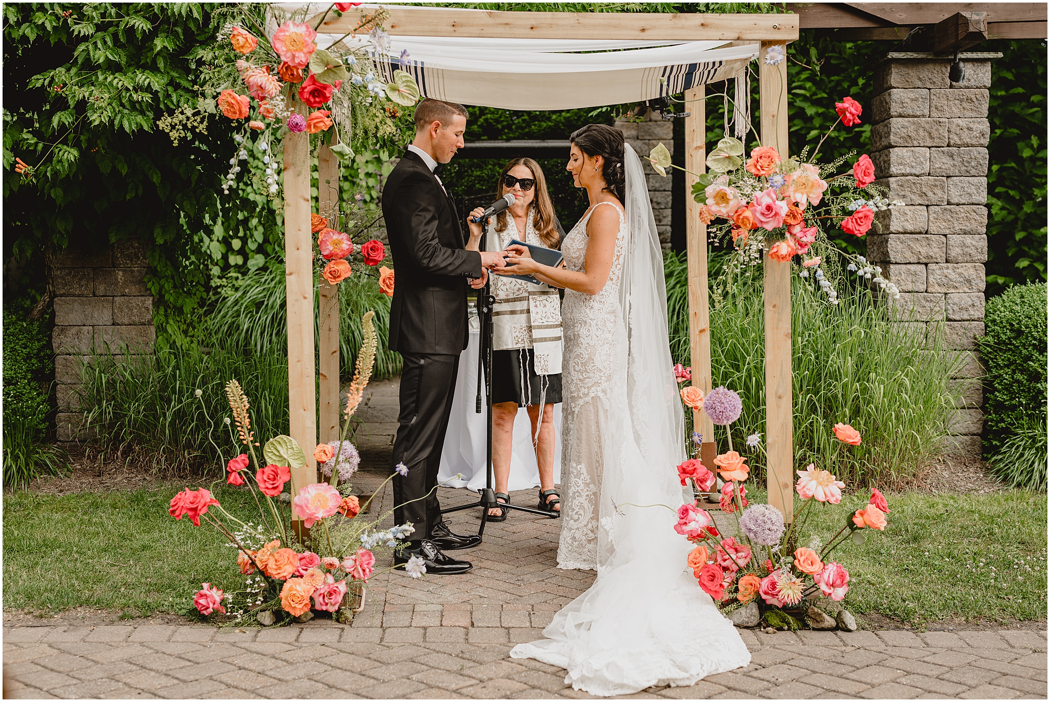 bride and groom hold hands under chuppah during wedding ceremony 