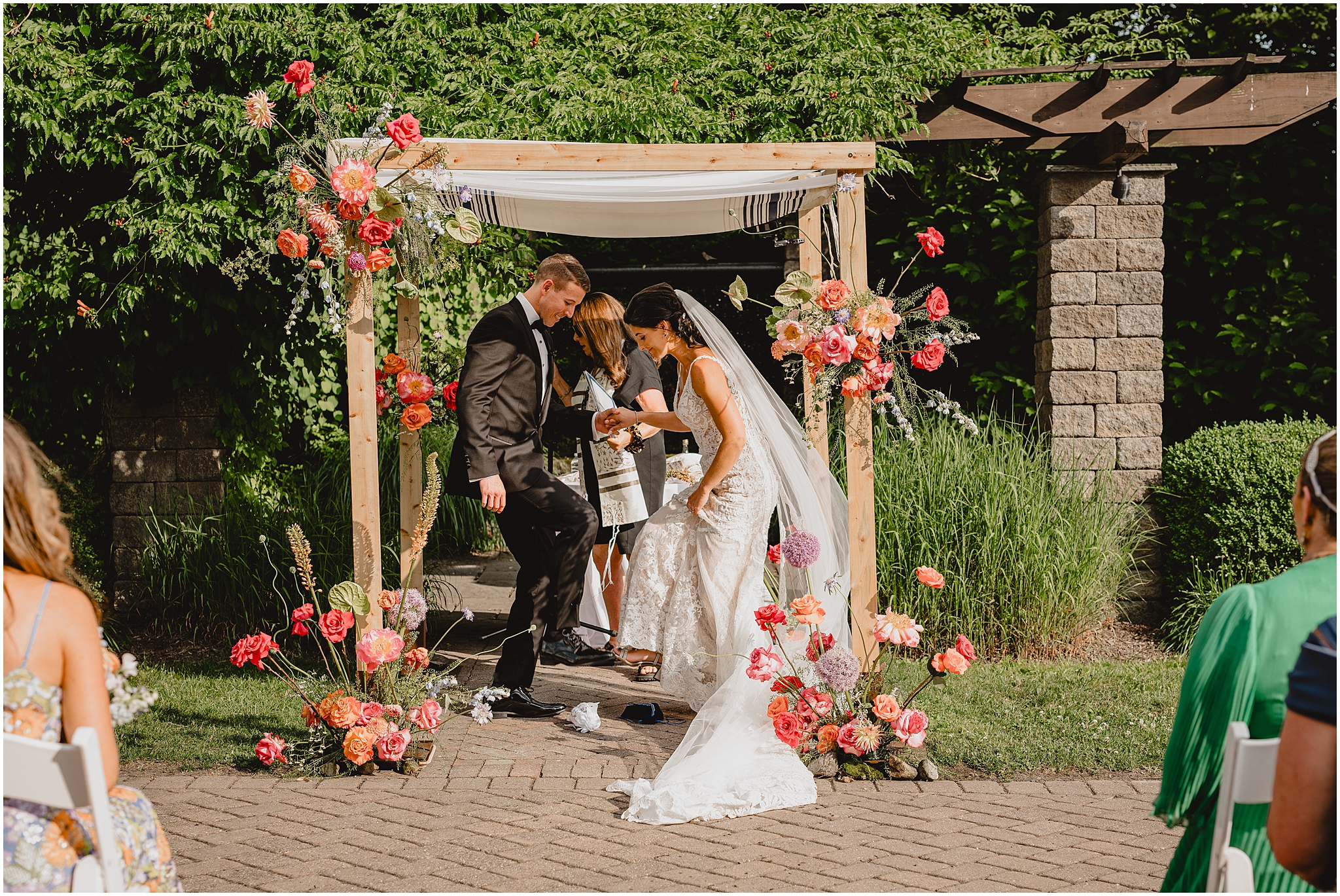newlyweds hold hands and break glass under arbor for ceremony at the Conservatory at Sussex County Fairgrounds
