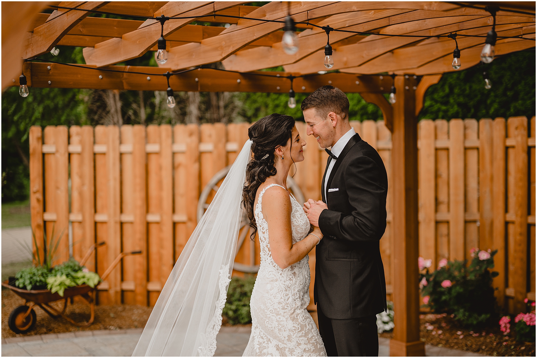 bride and groom hug under wooden arbor at the Conservatory at Sussex County Fairgrounds