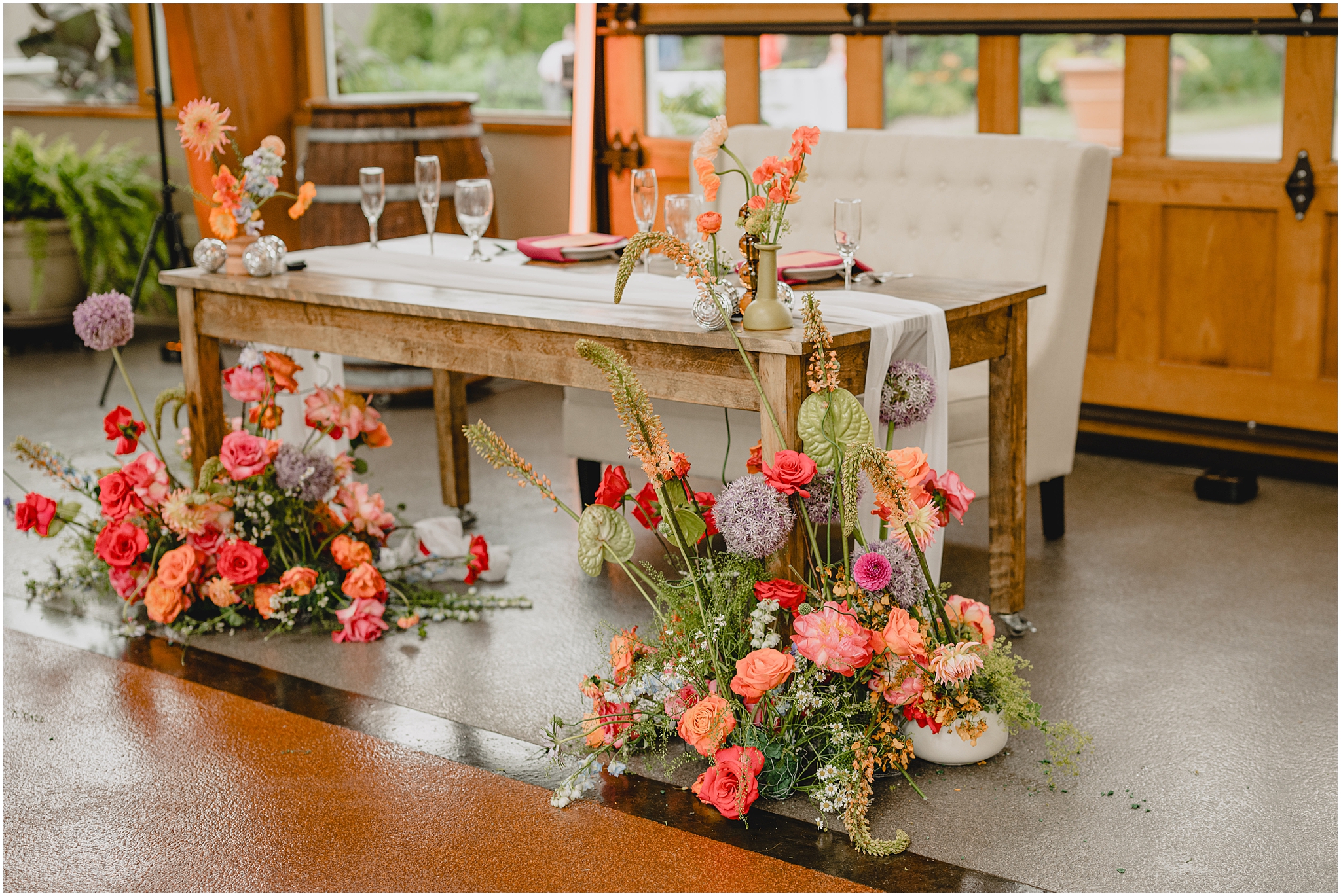 wooden sweetheart table with peach, coral, and pink flowers for reception at the Conservatory at Sussex County Fairgrounds