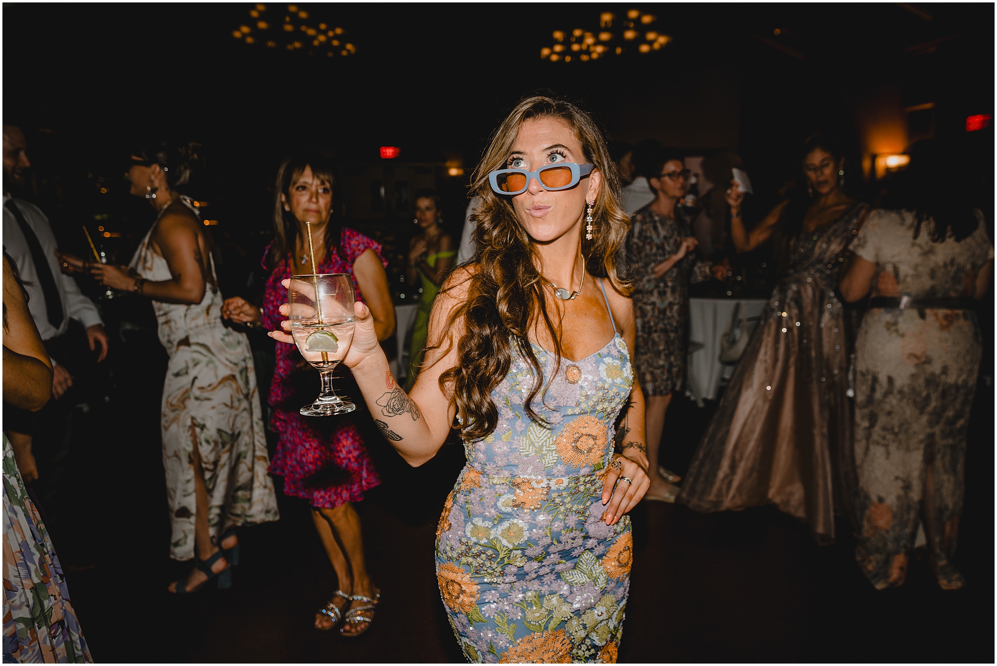 bridesmaid in embroidered dress dances with wine glass