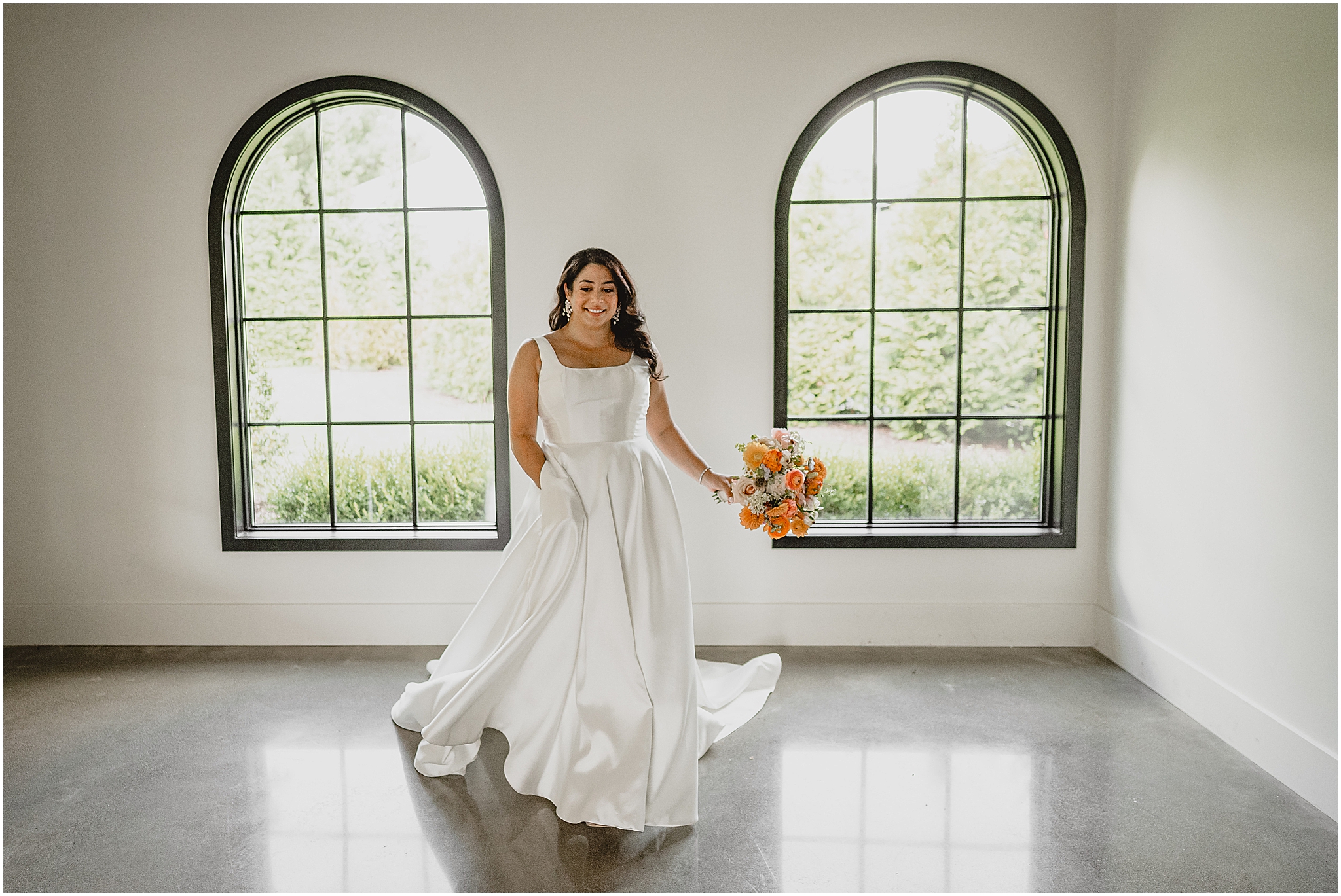 bride holds bouquet of coral and orange flowers twirling in wedding gown at the Perona Farms Refinery