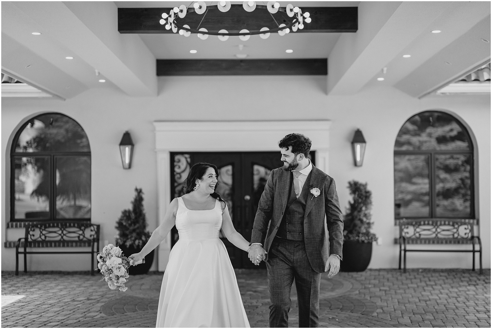 newlyweds hold hands laughing and walking outside the Perona Farms Refinery