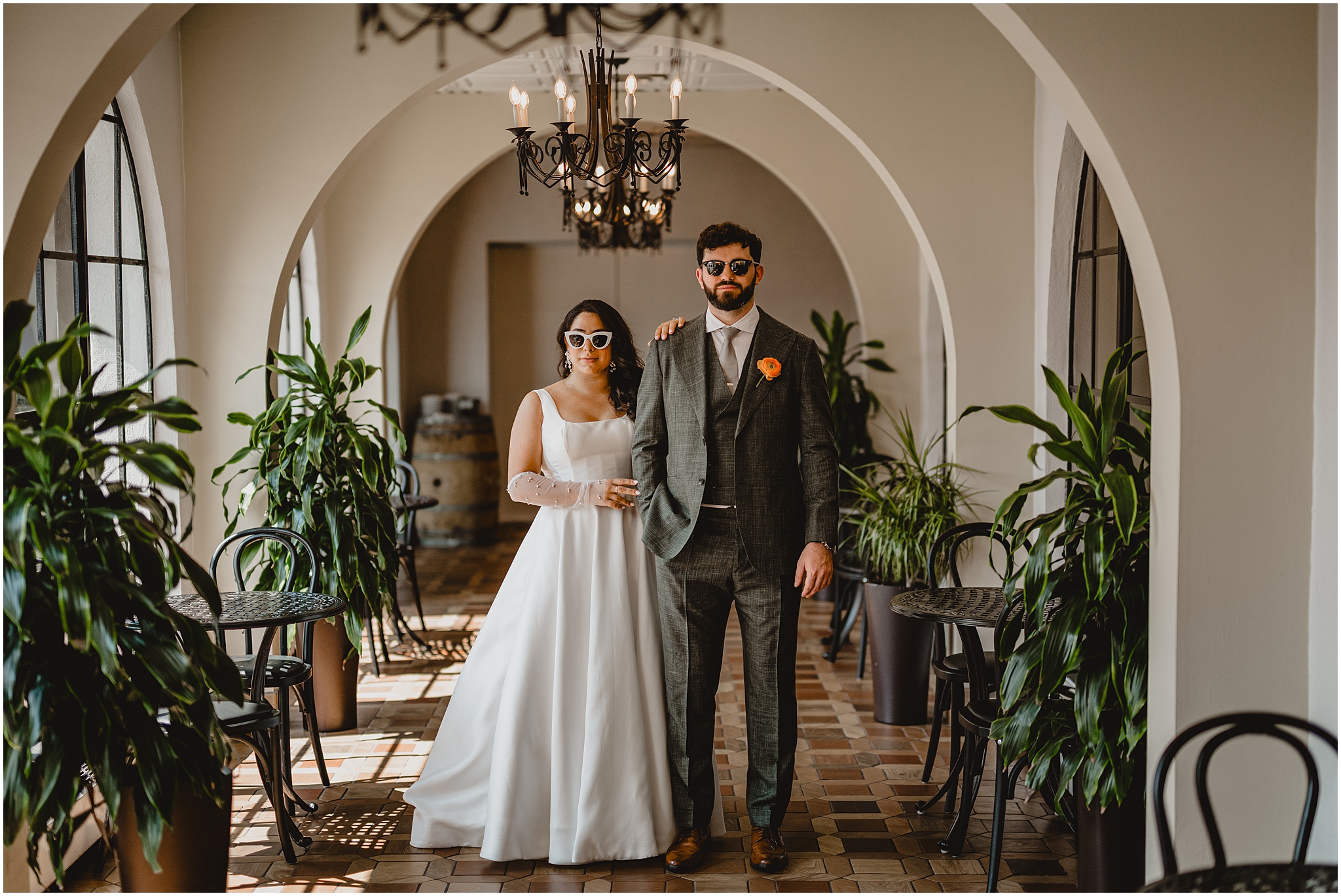 bride and groom stand inside hallway of the Perona Farms Refinery with white sunglasses on