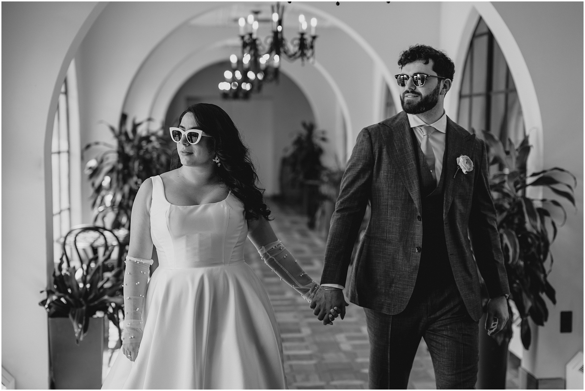 newlyweds hold hands walking together through hallway at the Perona Farms Refinery