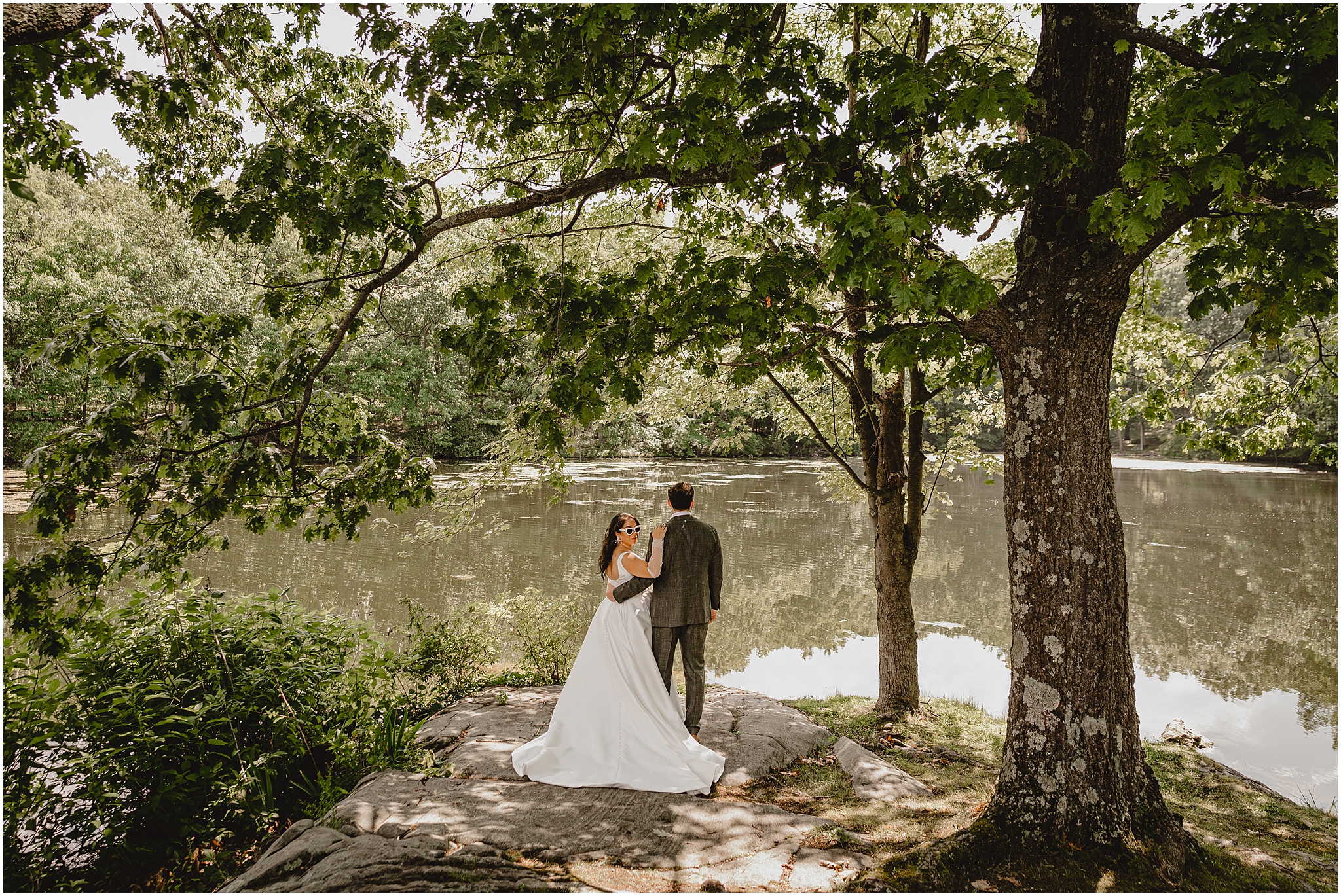 bride and groom hug near waterfront at the Perona Farms Refinery with bride looking over her shoulder