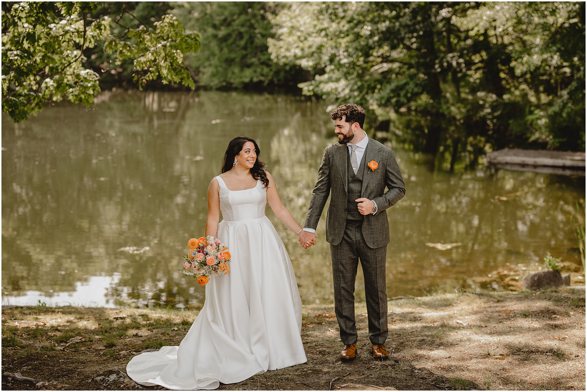bride and groom hold hands in front of river in Andover NJ