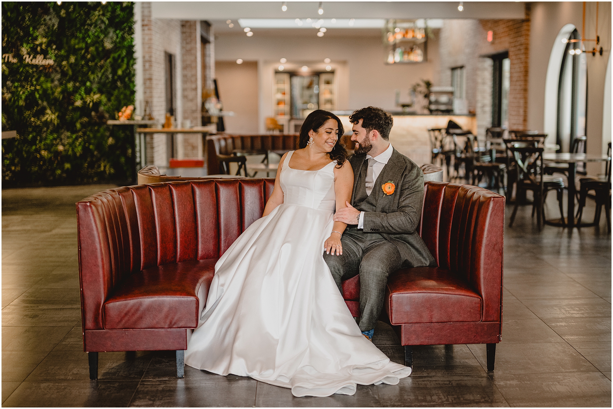 bride and groom sit on red leather couch inside restaurant in New Jersey