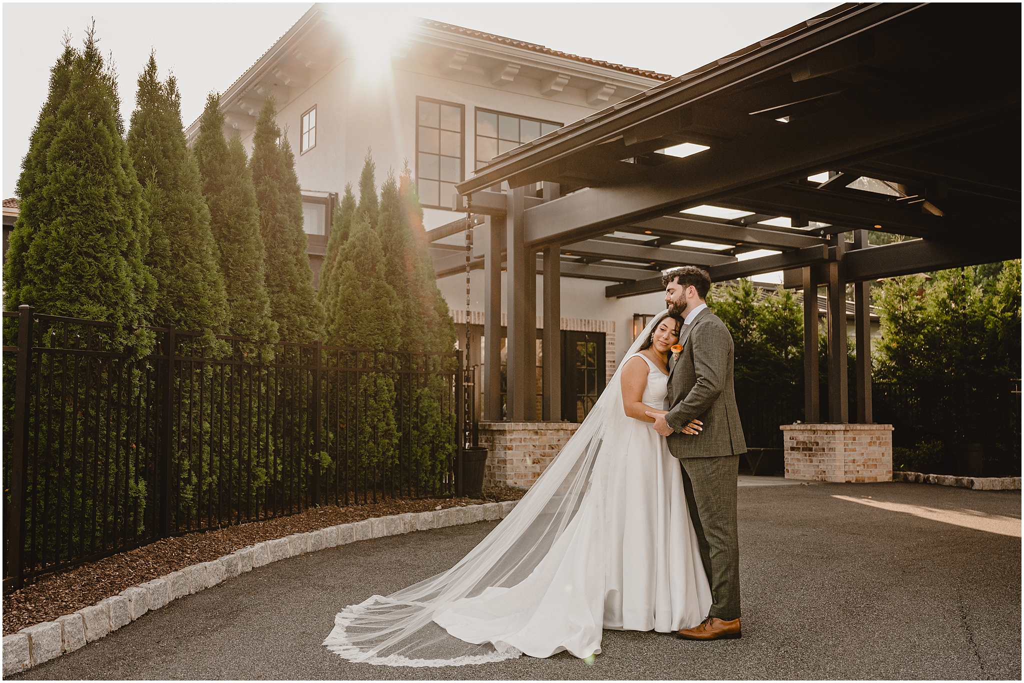 bride hugs groom leaning on his chest during summer wedding portraits at the Perona Farms Refinery