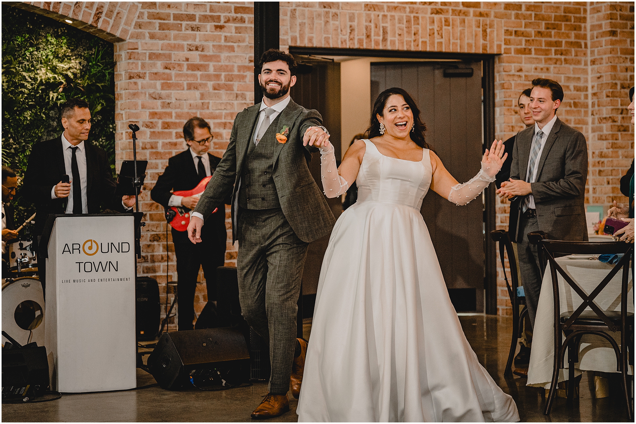 bride and groom smile walking into wedding reception by live band at the Perona Farms Refinery