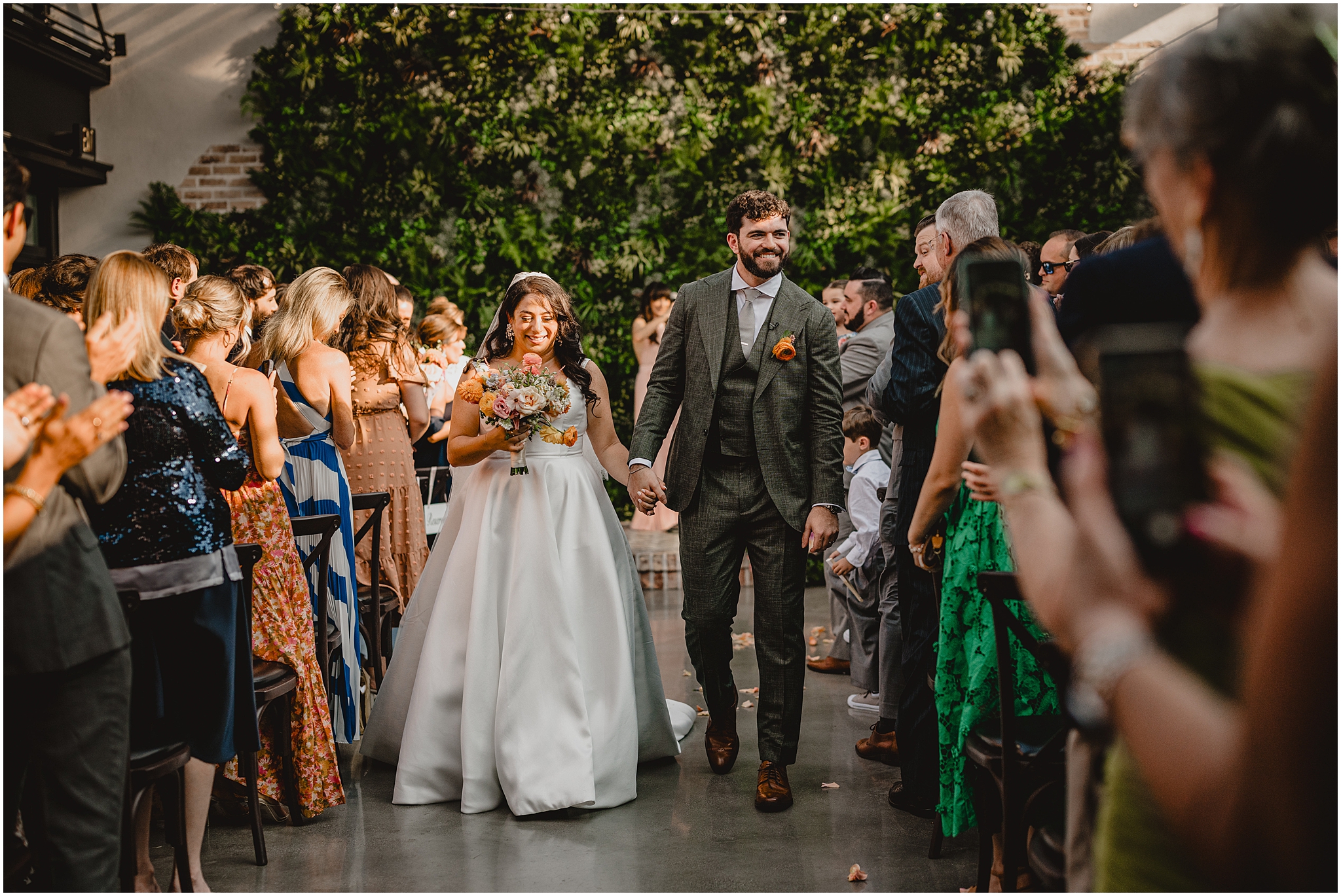 newlyweds hold hands walking up aisle during outdoor ceremony in Andover NJ