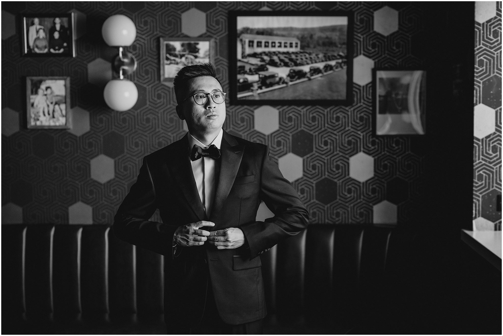 groom buttons up jacket in front of geometric wall in groom's room at the Refinery at Perona Farms