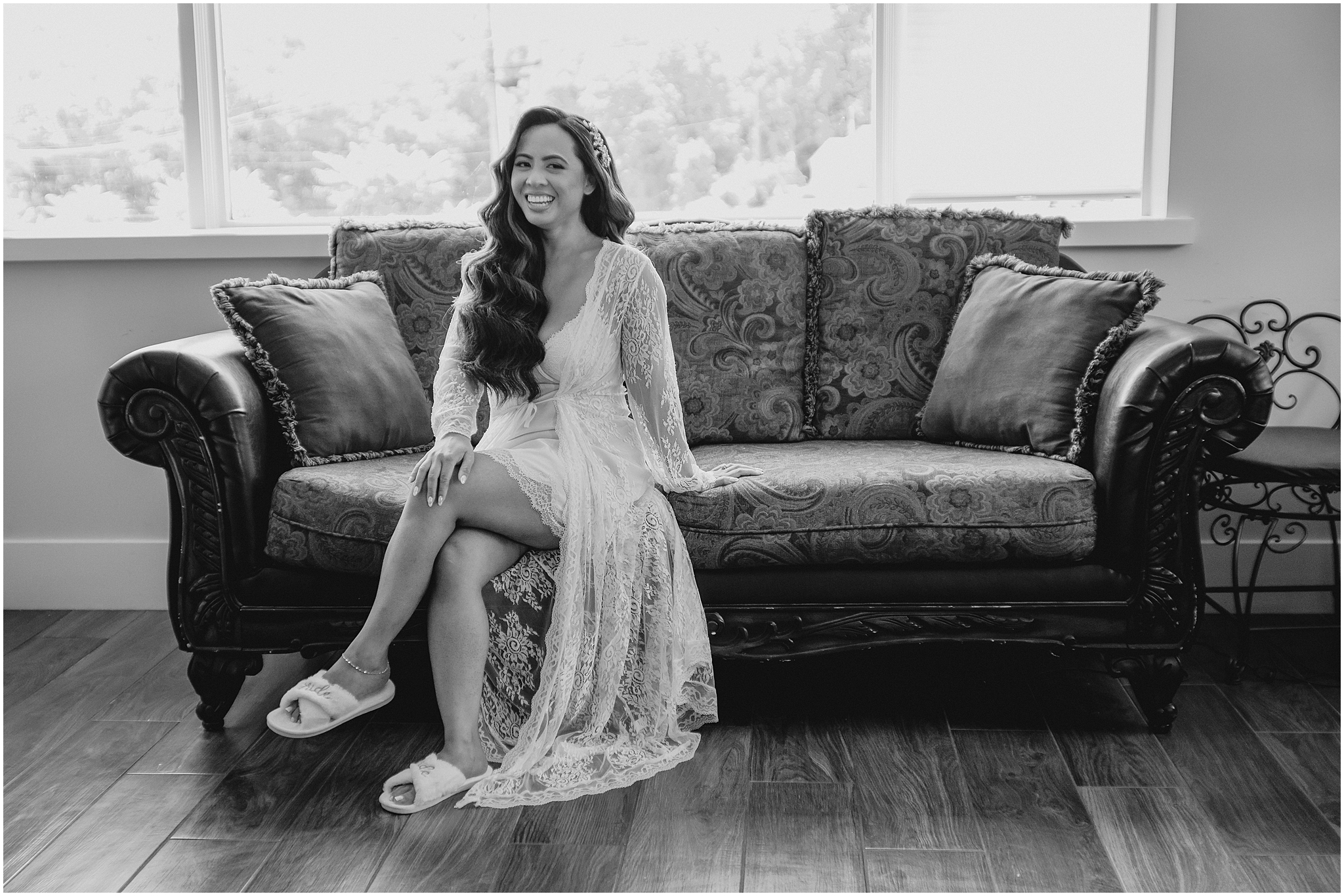 bride sits on couch in lace robe and slippers on wedding day