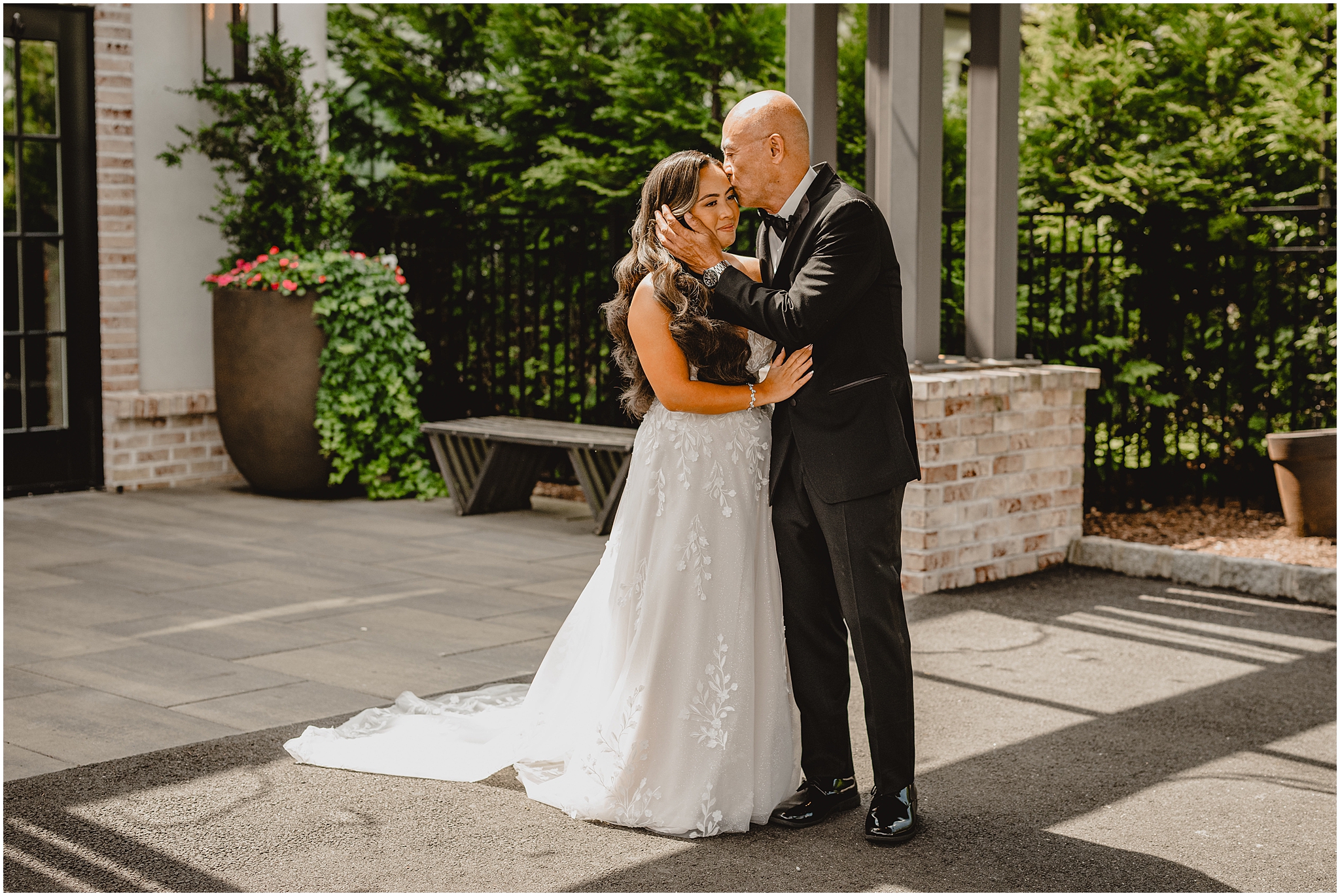 dad hugs bride kissing her forehead on patio at the Refinery at Perona Farms