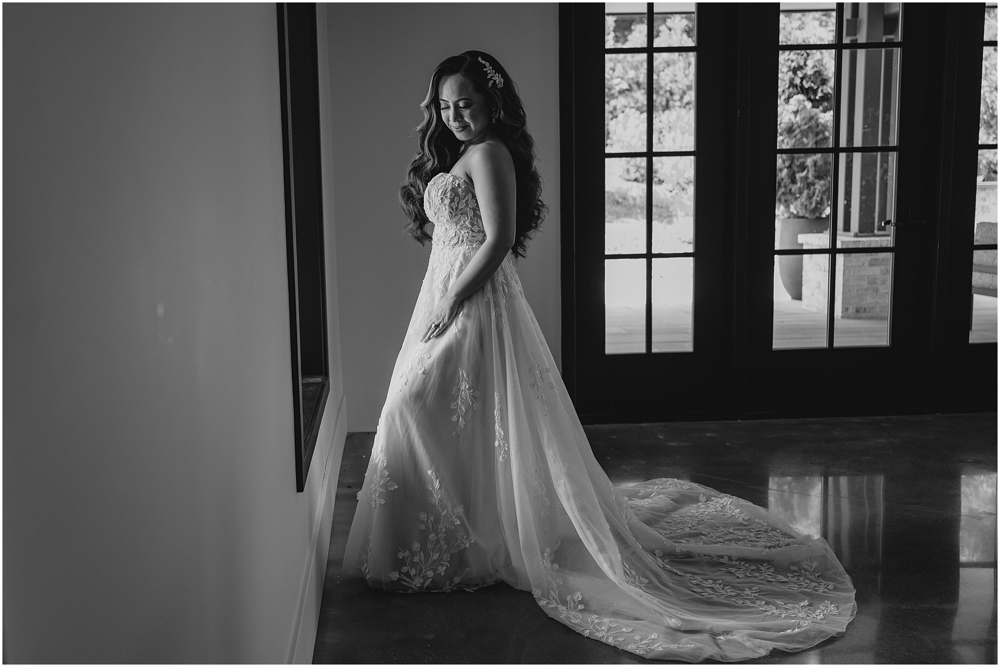 bride stands facing window at the Refinery at Perona Farms with hands in the pockets of her wedding dress