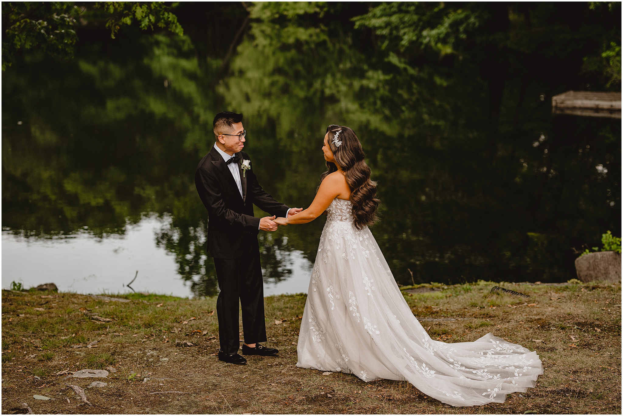 newlyweds reach for each other during first look by the pond at the Refinery at Perona Farms