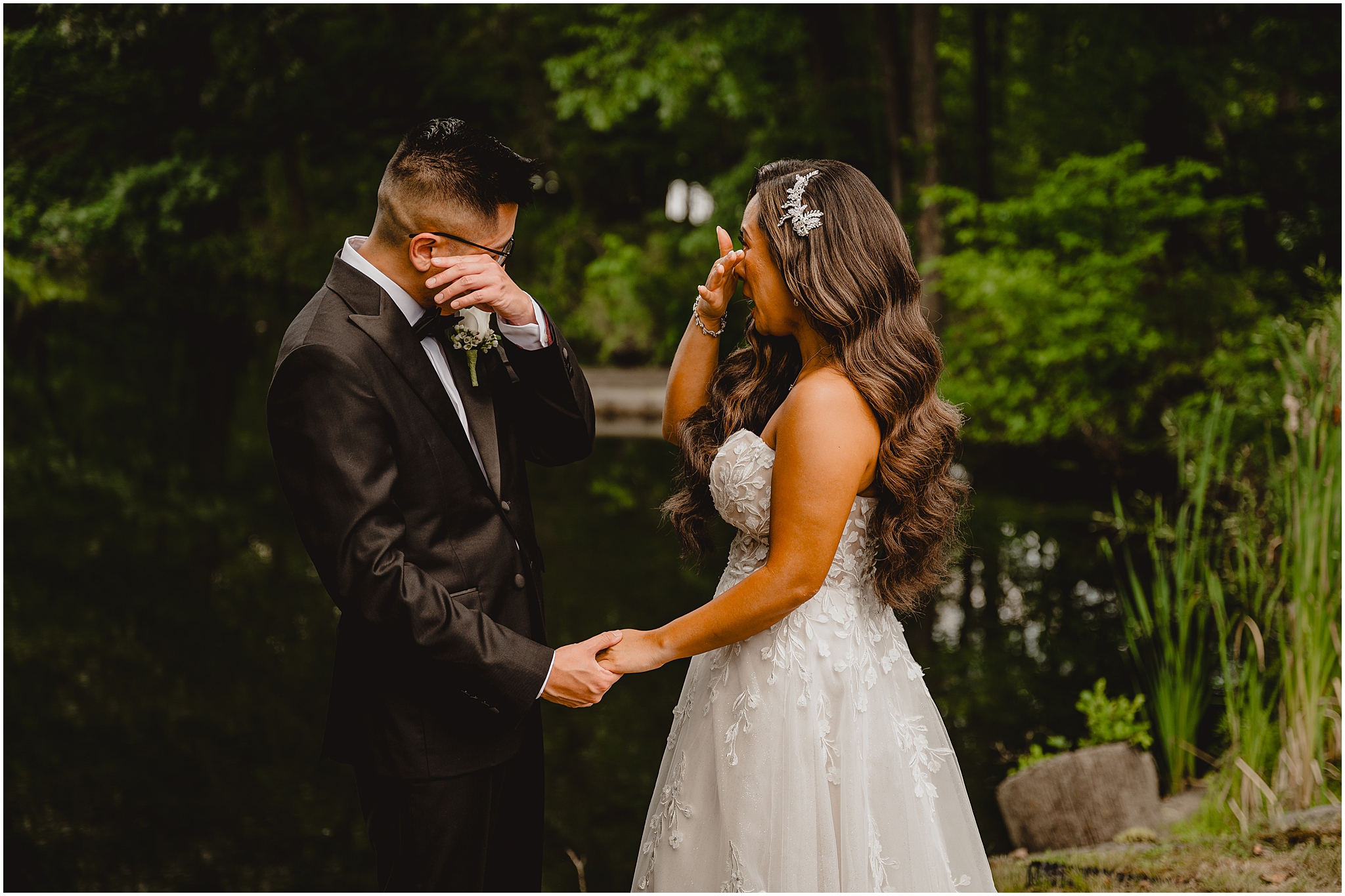 bride and groom hold hands and wipe tears from their eyes during first look