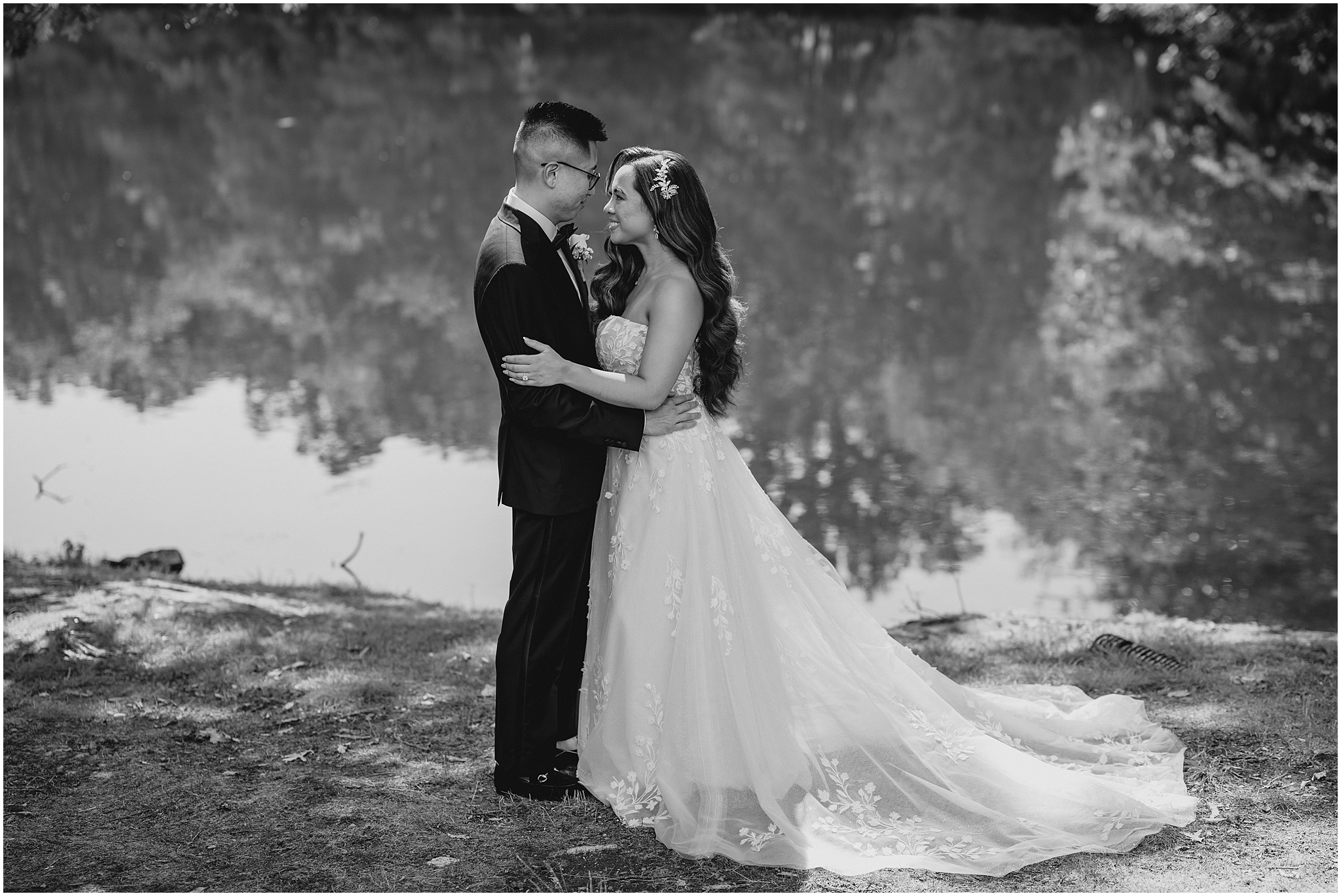 bride and groom face each other hugging near pond in Andover NJ
