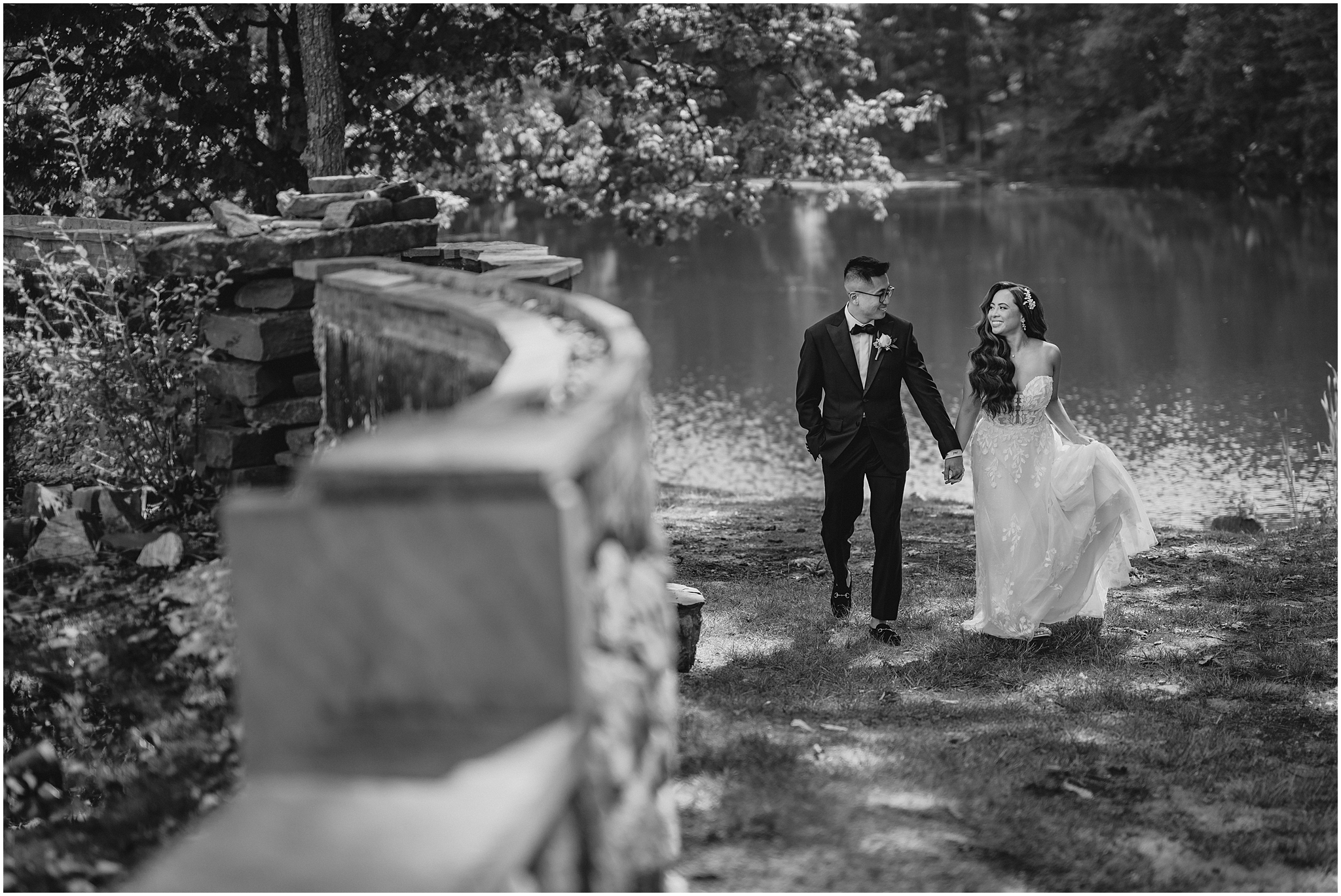 bride and groom hold hands walking near lake outside the Refinery at Perona Farms