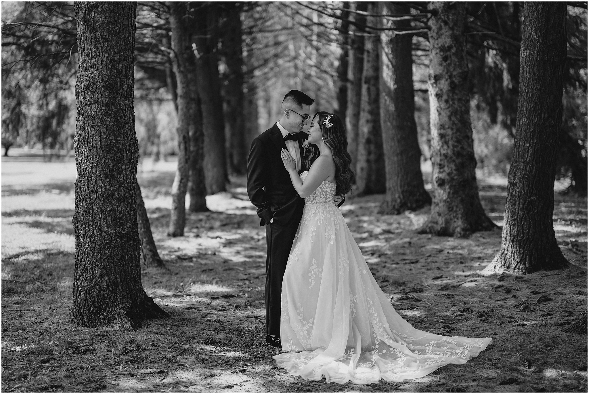 bride and groom lean together between rows of trees at the Refinery at Perona Farms