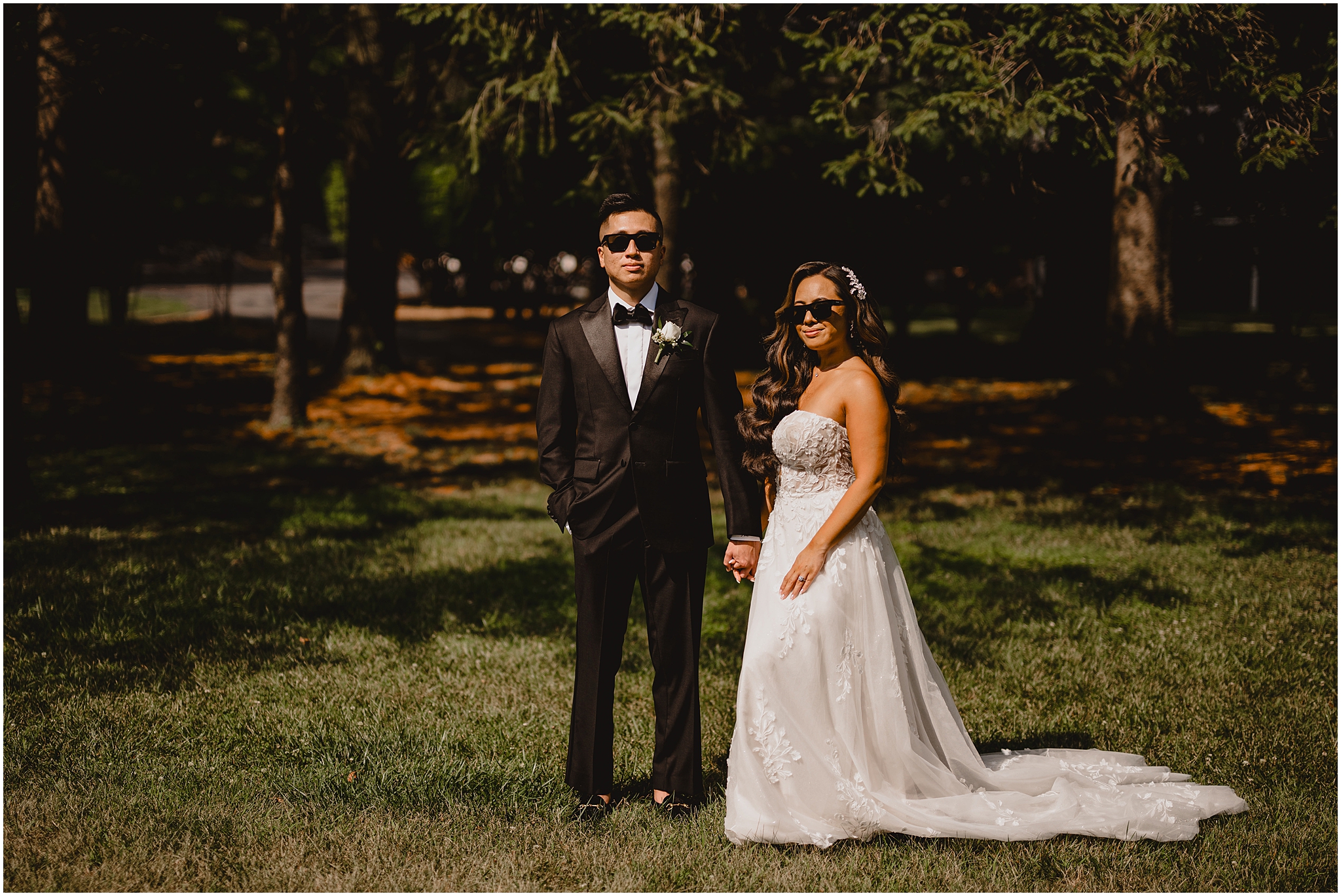 bride and groom hold hands wearing sunglasses near forest at the Refinery at Perona Farms