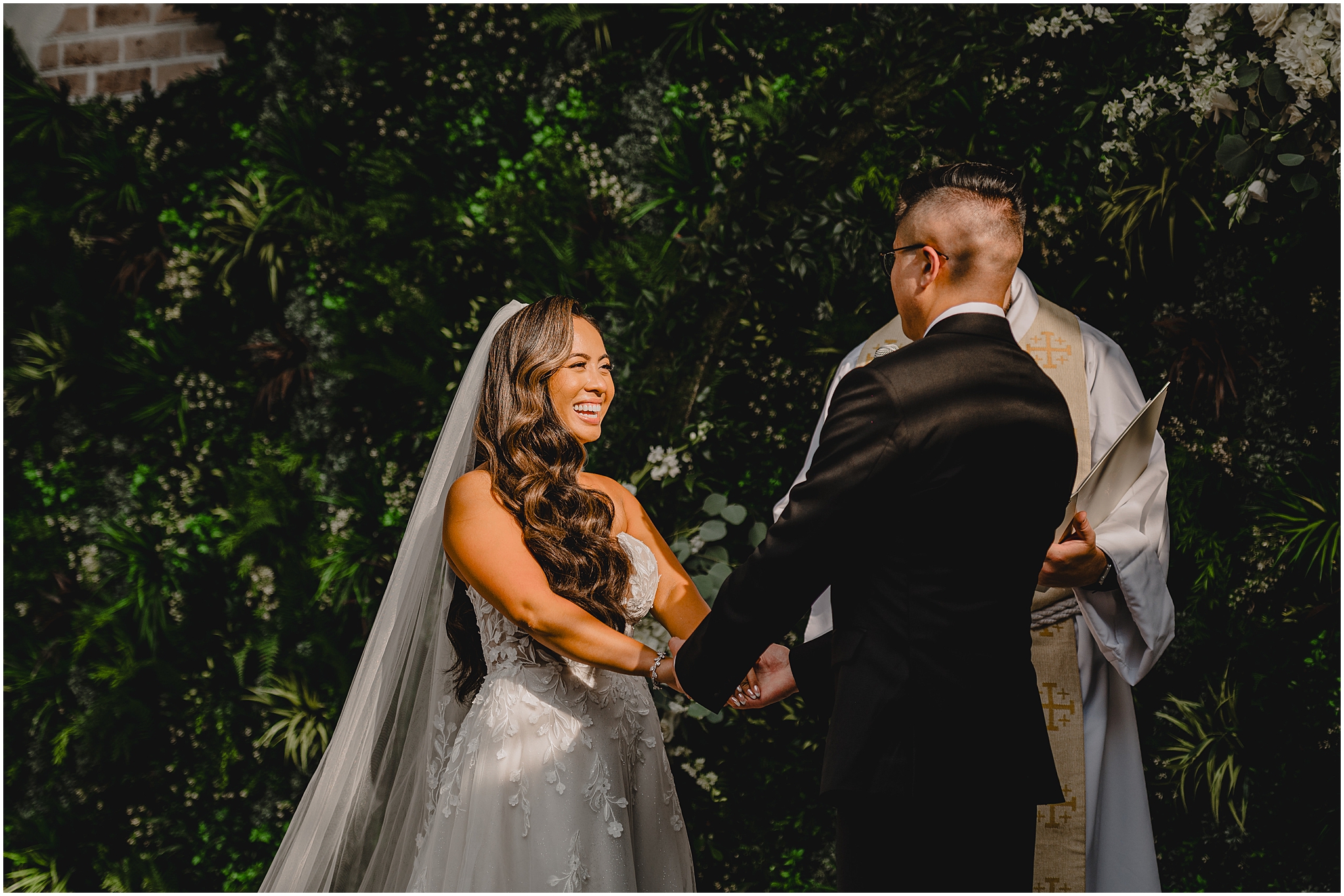bride laughs holding groom's hands during ceremony in courtyard in New Jersey