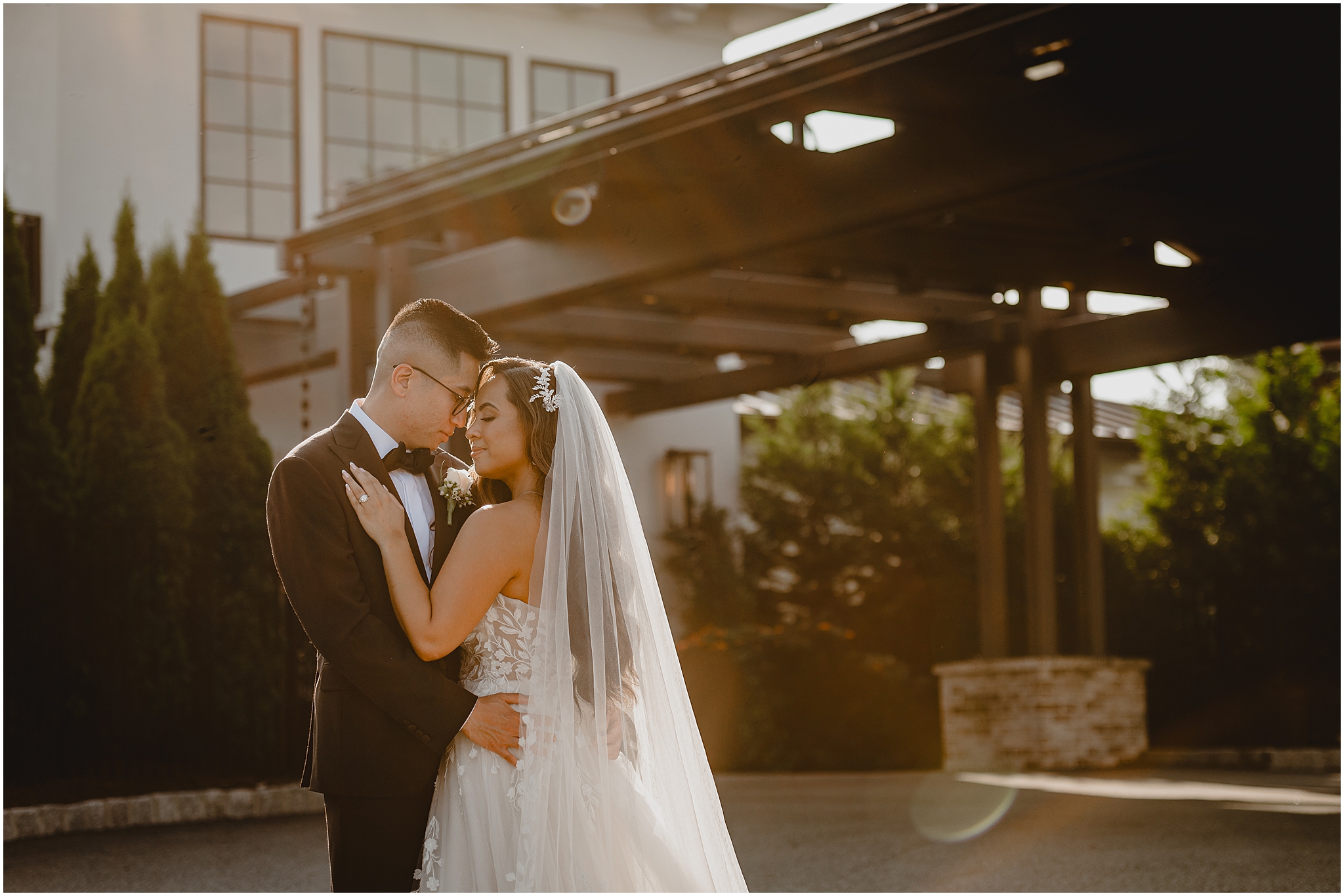 bride lays hand on groom's chest leaning heads together outside the Refinery at Perona Farms