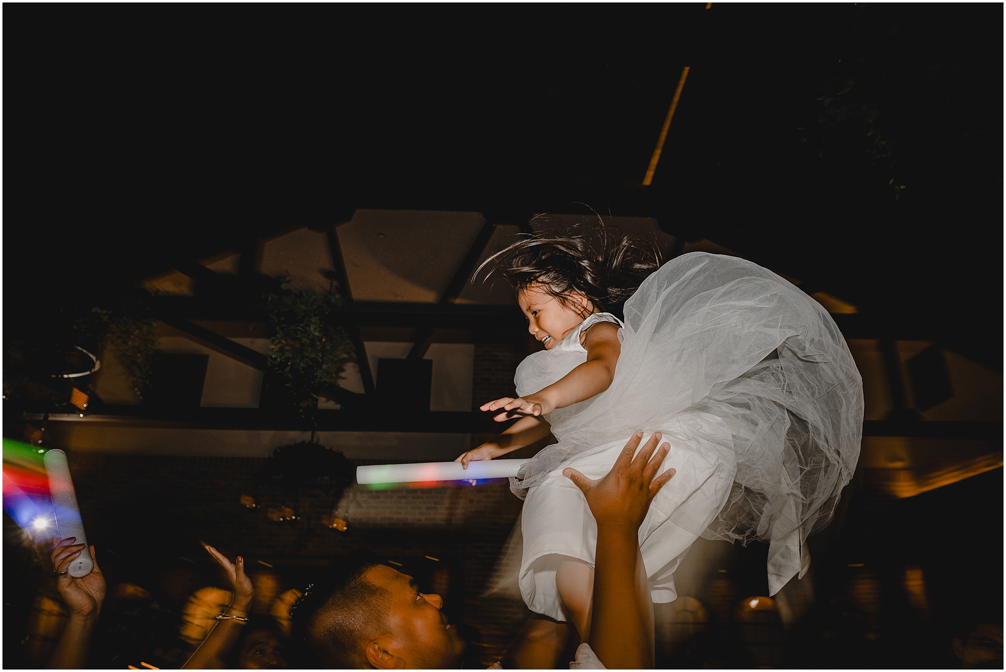 guest tosses daughter in the air during reception holding onto glow stick