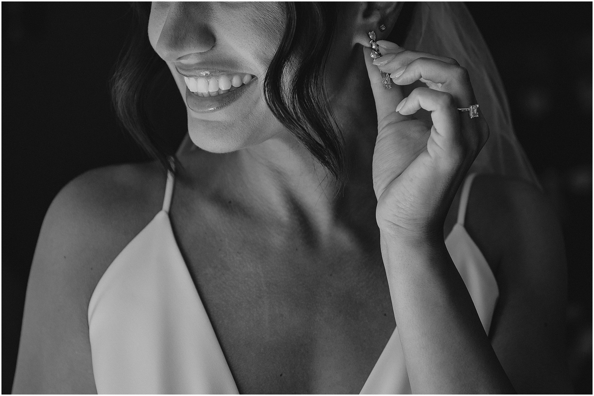 bride holds out drop earring in chic wedding dress