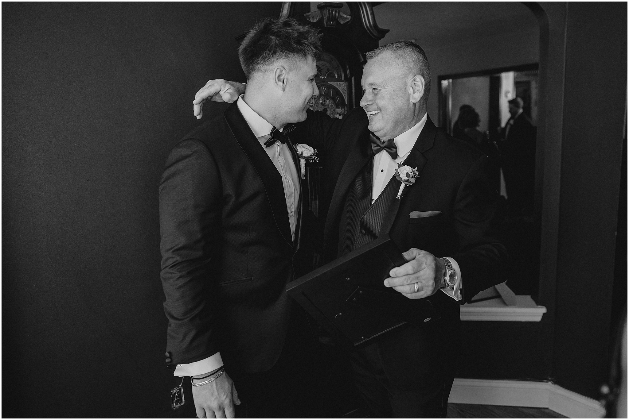 dad hugs groom laughing during wedding day prep in Jersey City