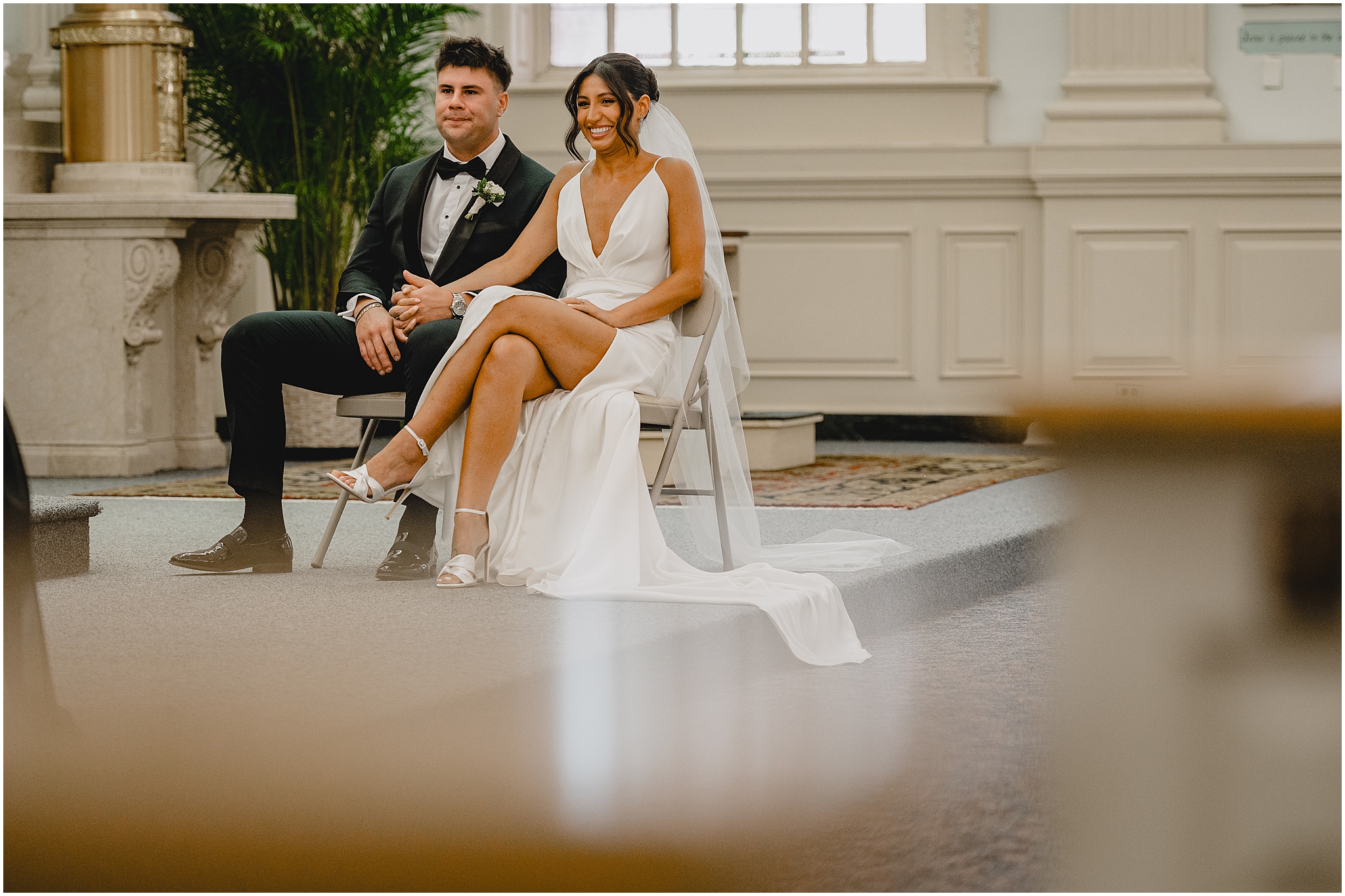 bride and groom hold hands sitting by alter during wedding ceremony 