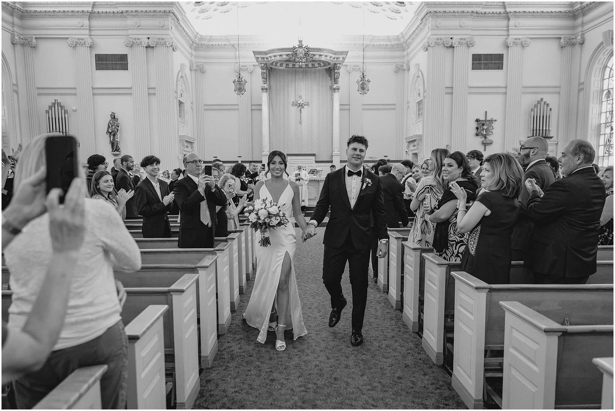 newlyweds hold hands walking up aisle in New Jersey church