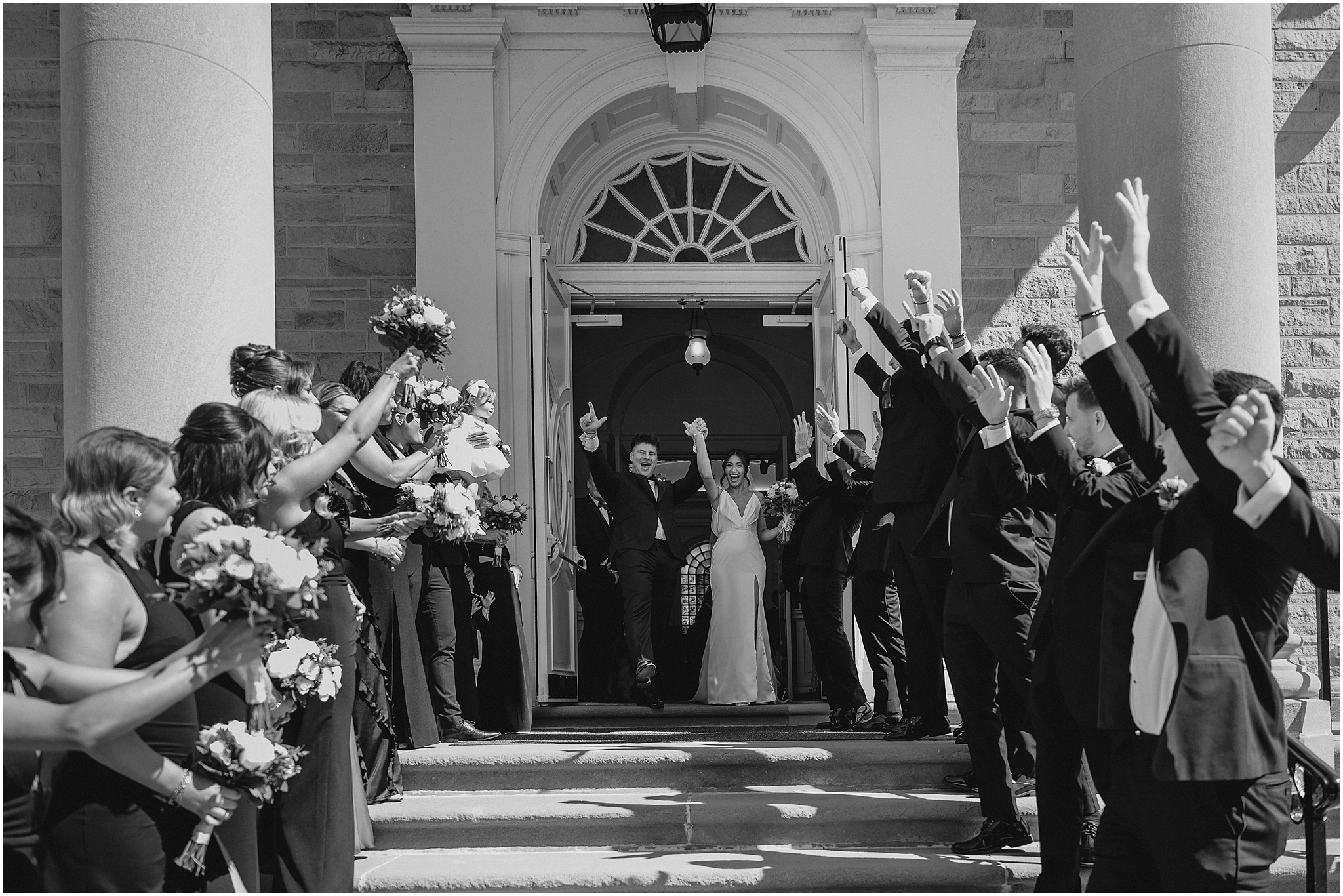 bride and groom exist church while weddings party cheers on steps of church 