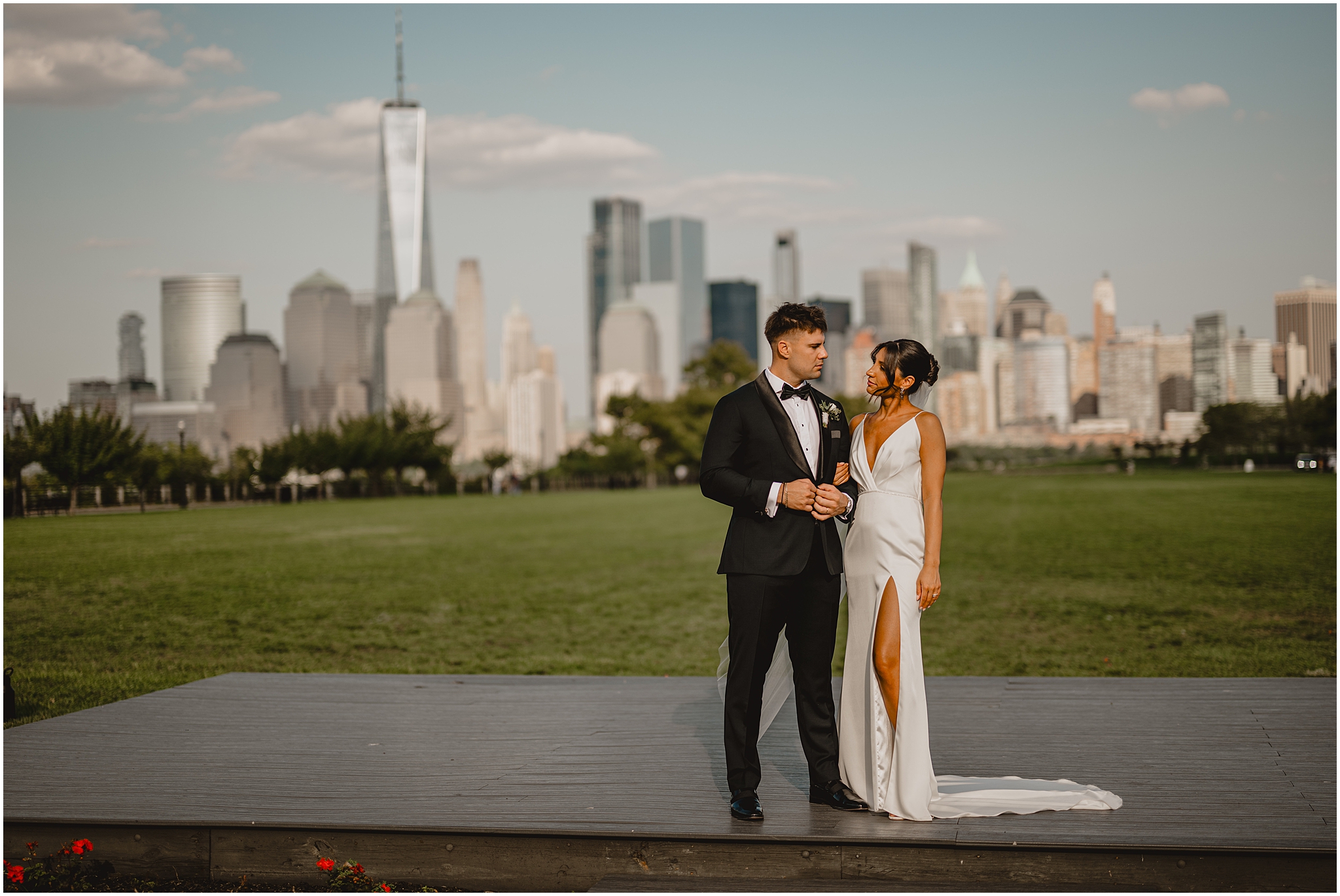 bride and groom stand together in front of Manhattan skyline on wooden platform