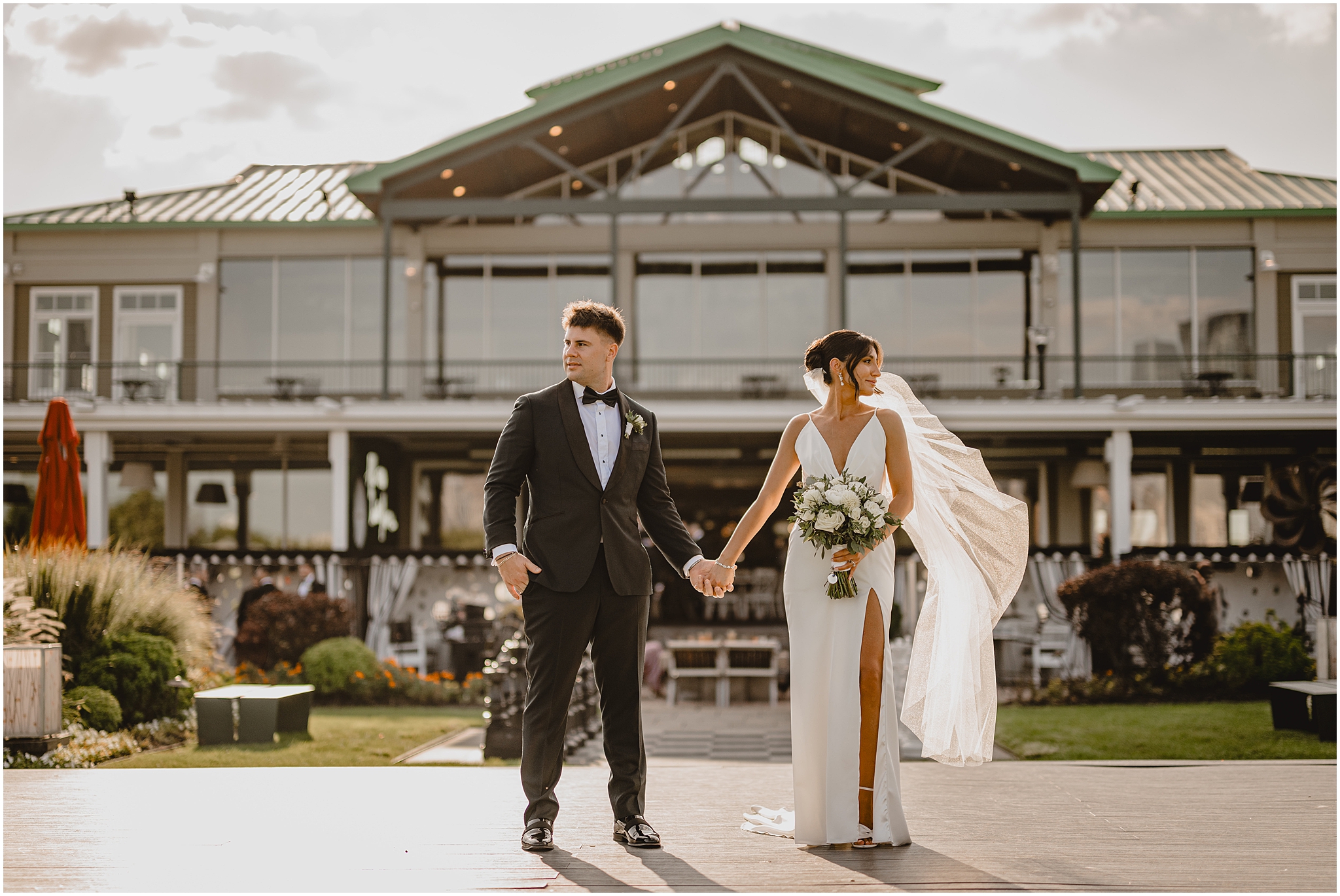 newlyweds hold hands in front of the Liberty House in Jersey City
