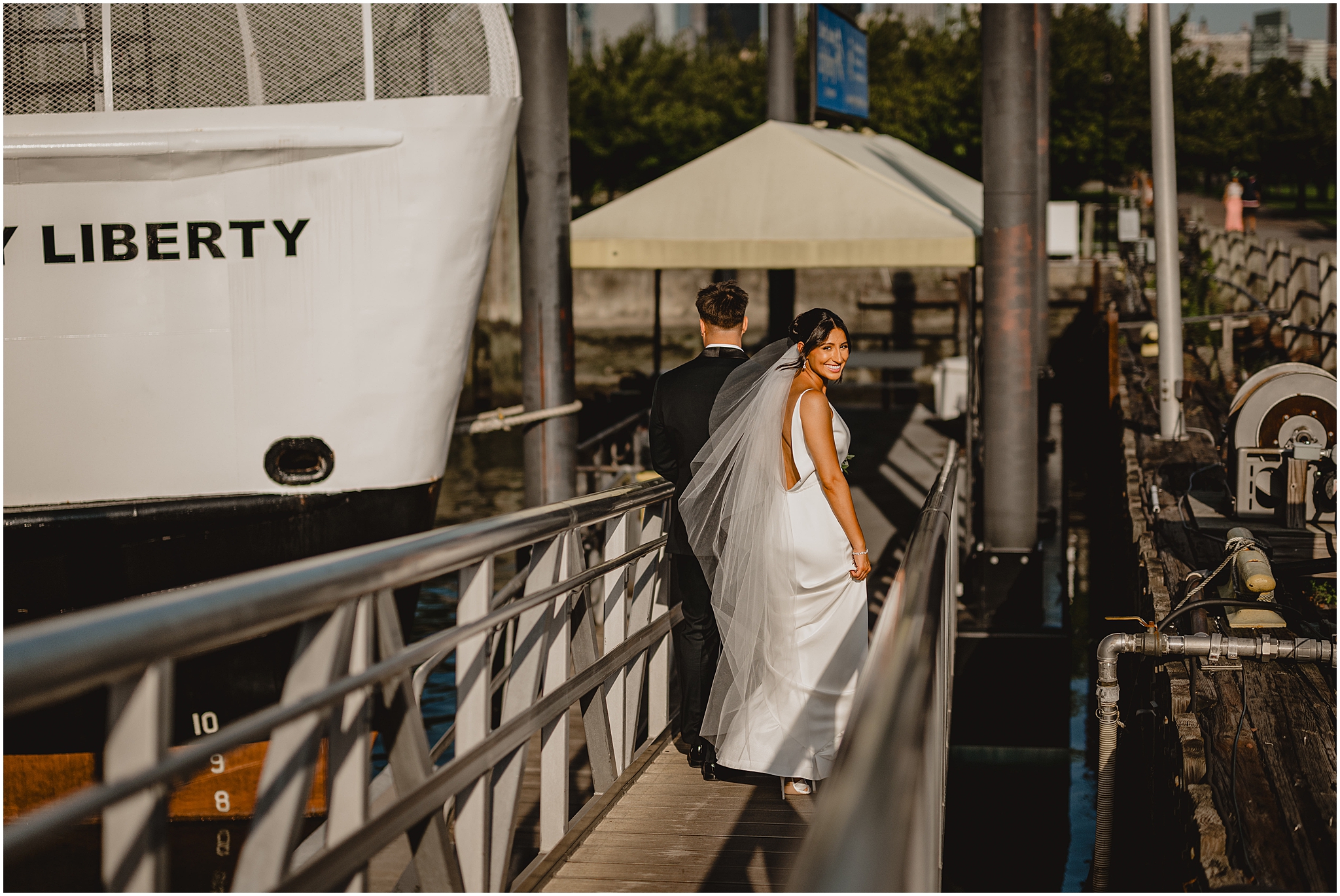 groom leads bride up plank towards boat in Jersey City 