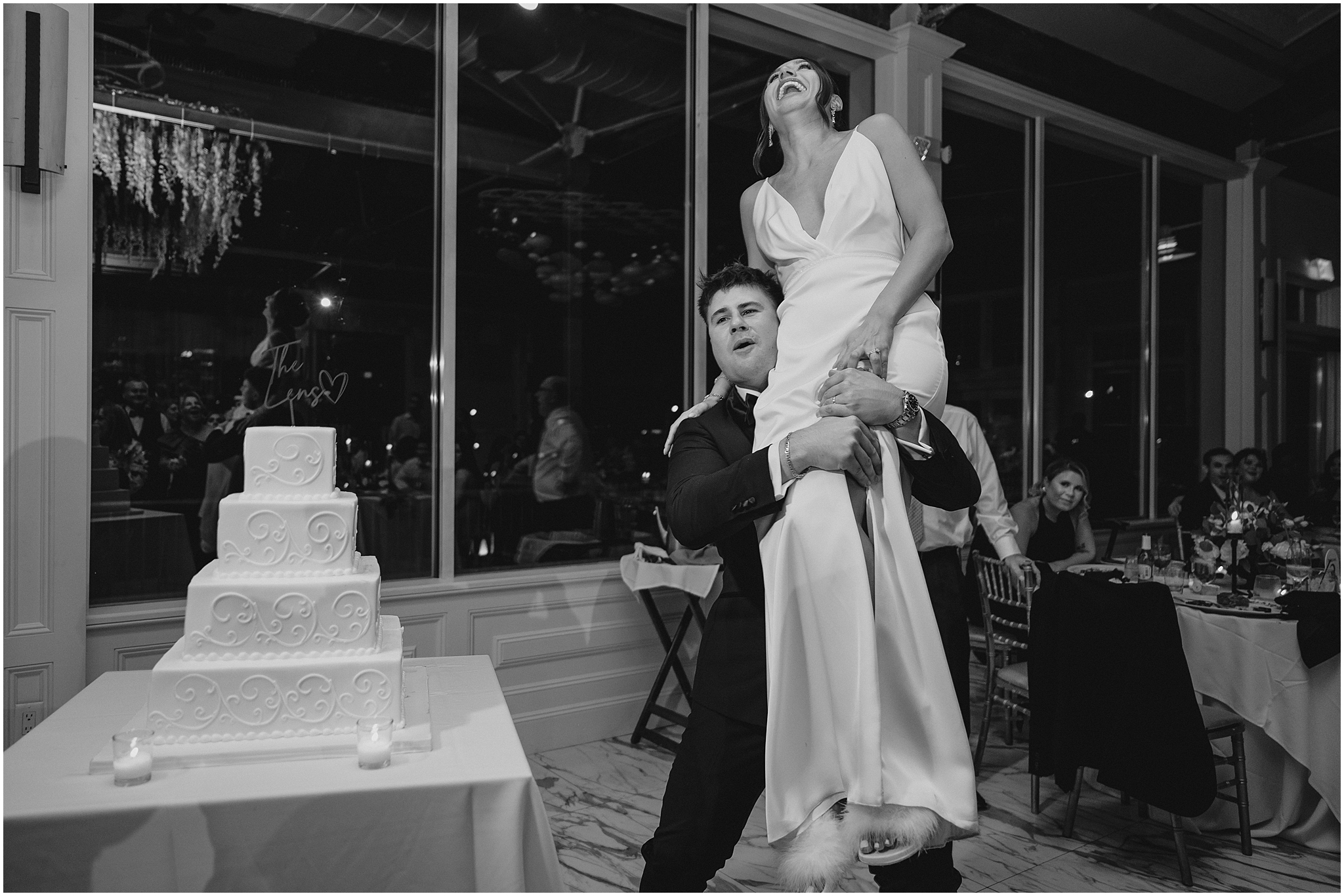 groom lifts up bride by wedding cake during Liberty House wedding reception
