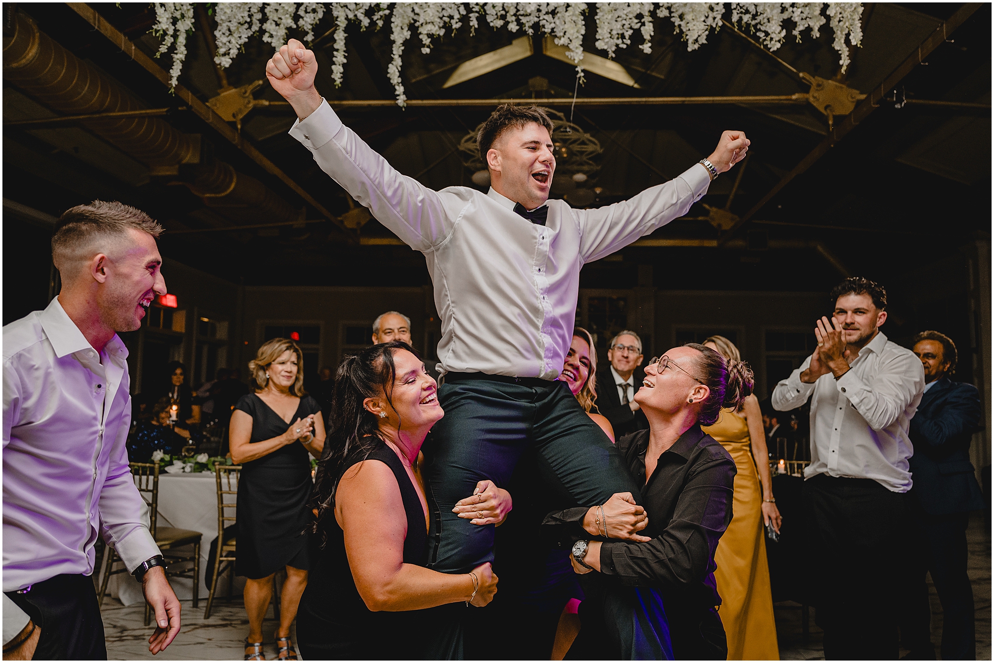 guests lift up groom while he cheers during Liberty House wedding reception