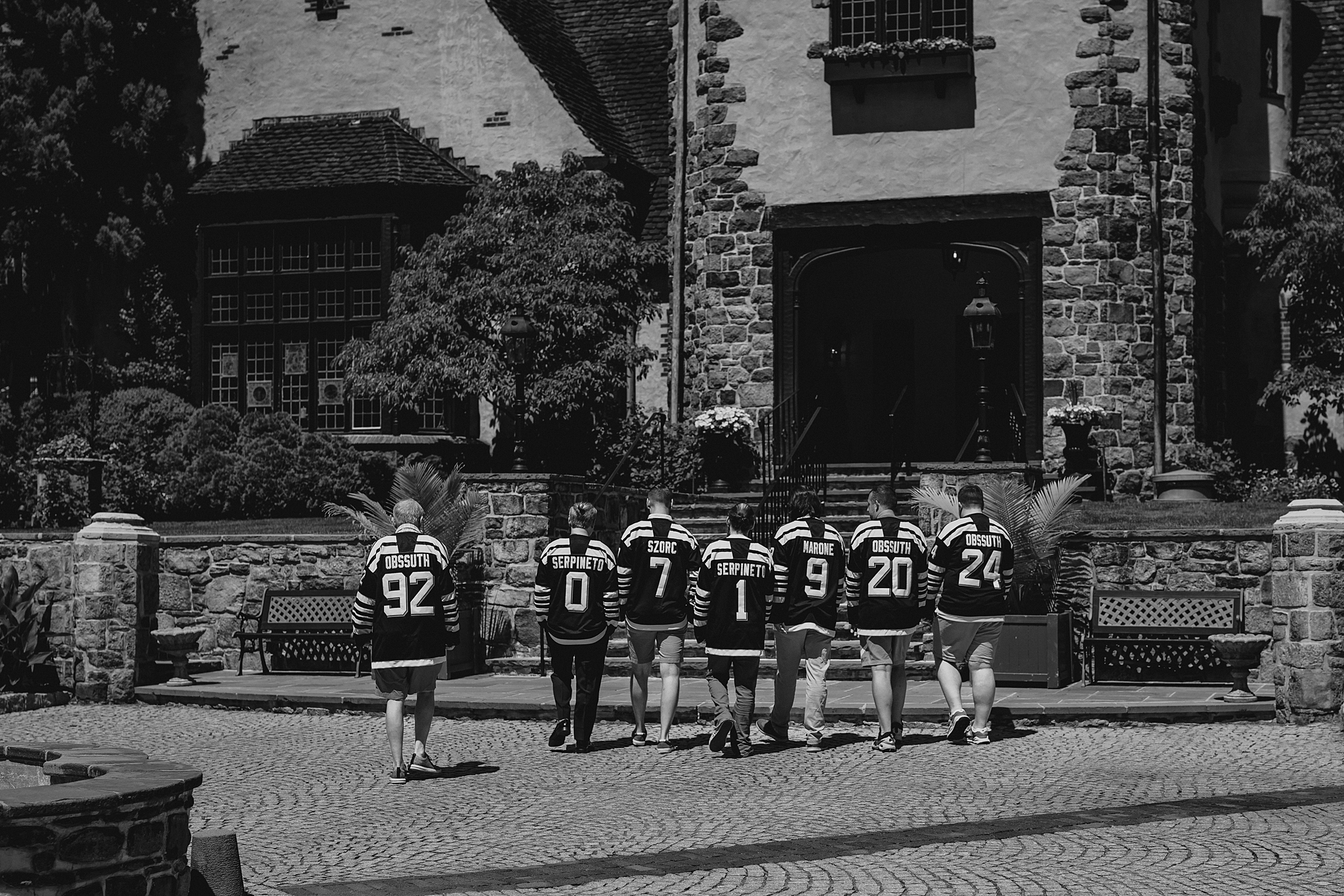 groomsmen walk into Pleasantdale Chateau wearing custom hockey jerseys