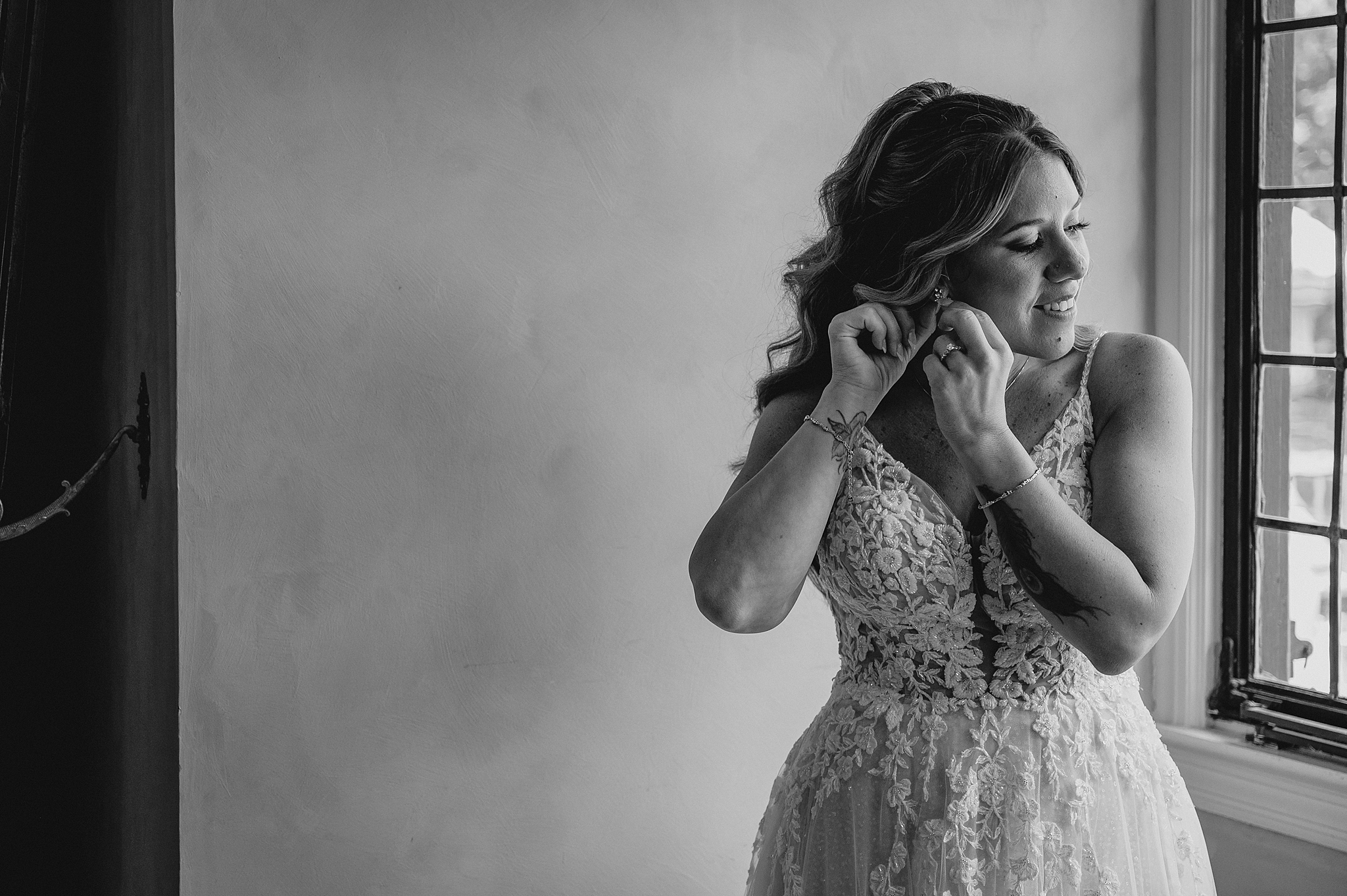 bride adjusts earrings while preparing for summer wedding day in New Jersey