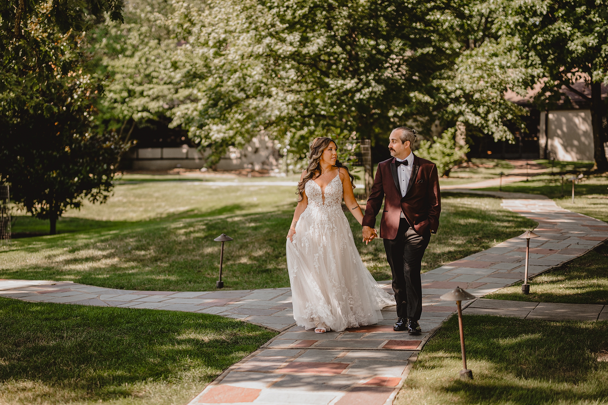 bride and groom hold hands walking down pathway outside Pleasantdale Chateau