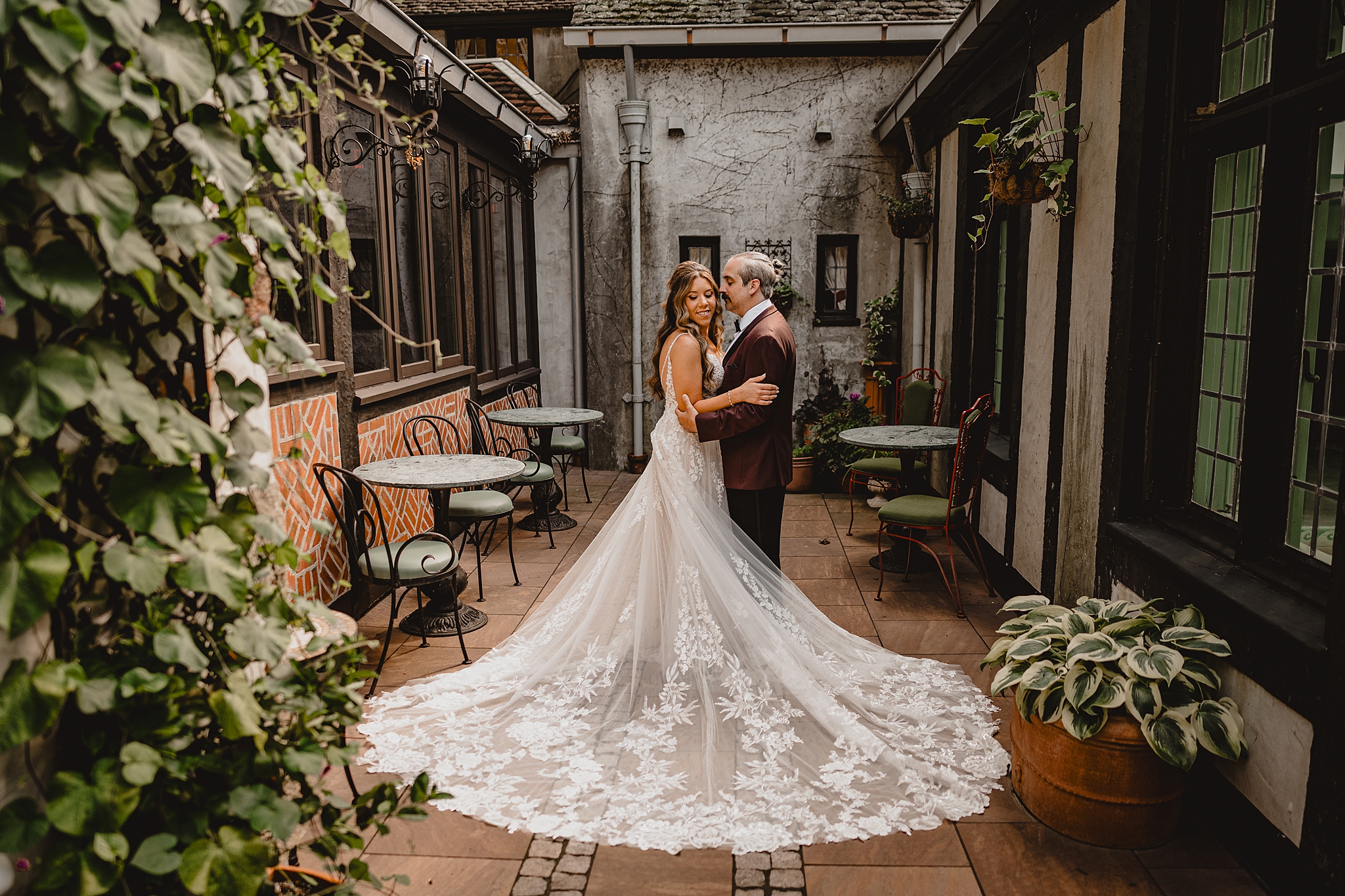 bride and groom hug on patio with green plants all around them at Pleasantdale Chateau