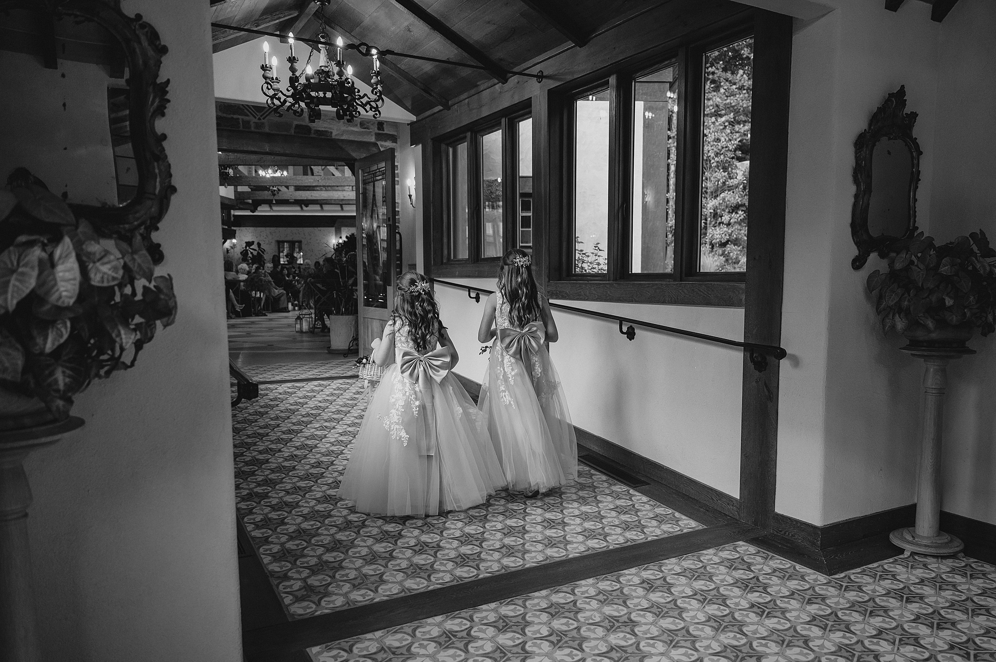 flower girls walk down hallway inside Pleasantdale Chateau